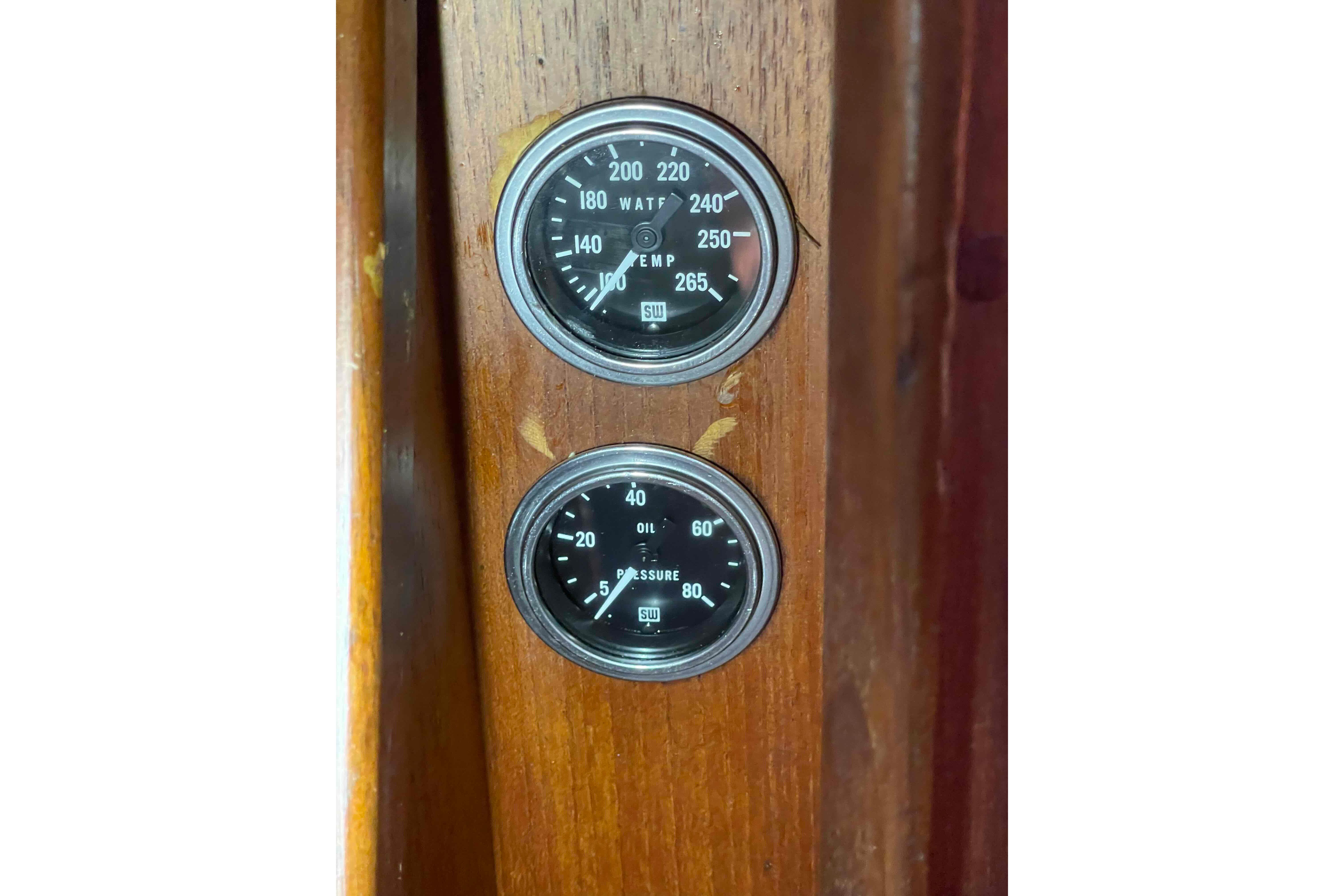 1989 Island Packet 35 boat gauges on wooden panel, displaying temperature and oil pressure.