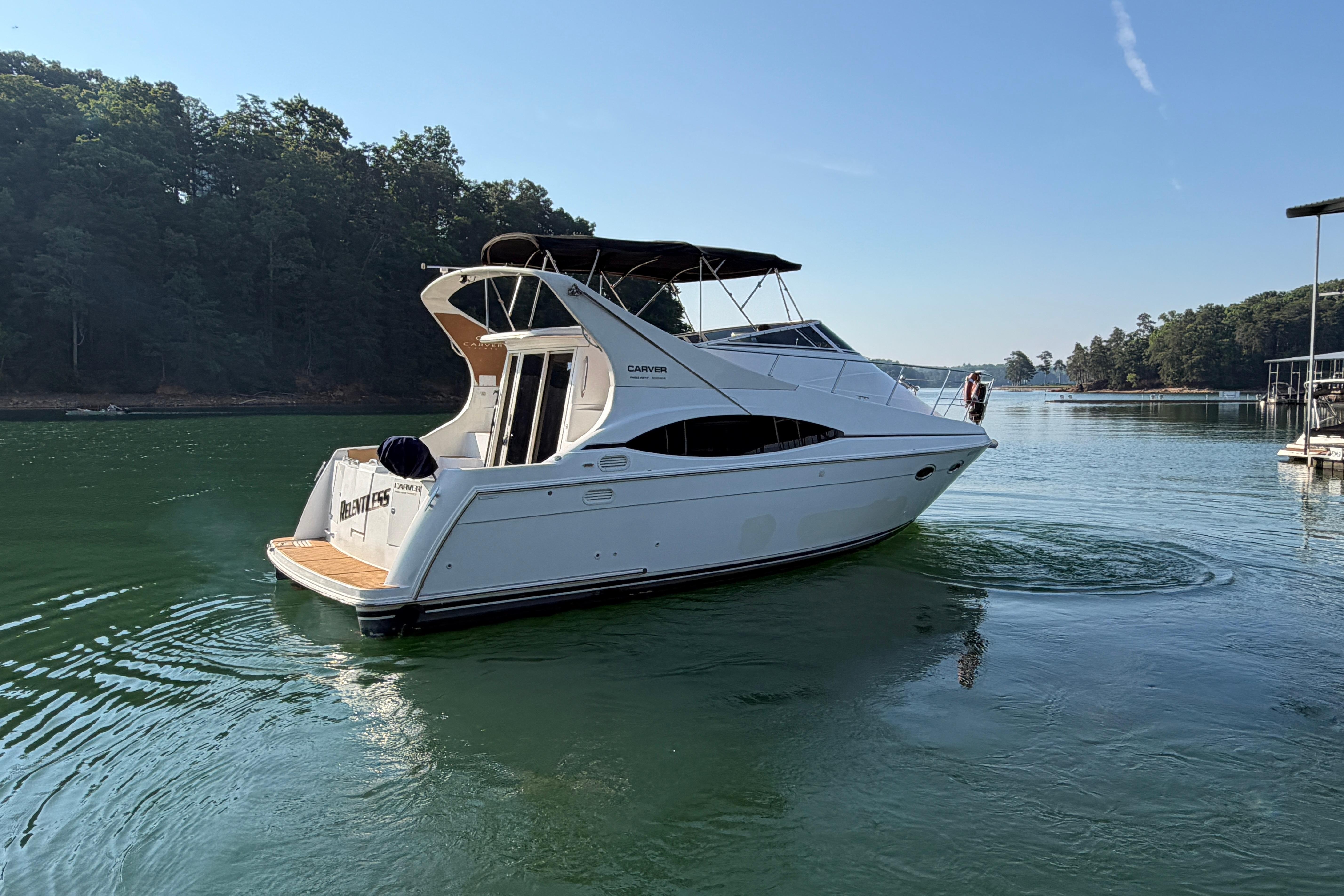 2003 Carver 350 Mariner yacht on serene lake, surrounded by lush trees.