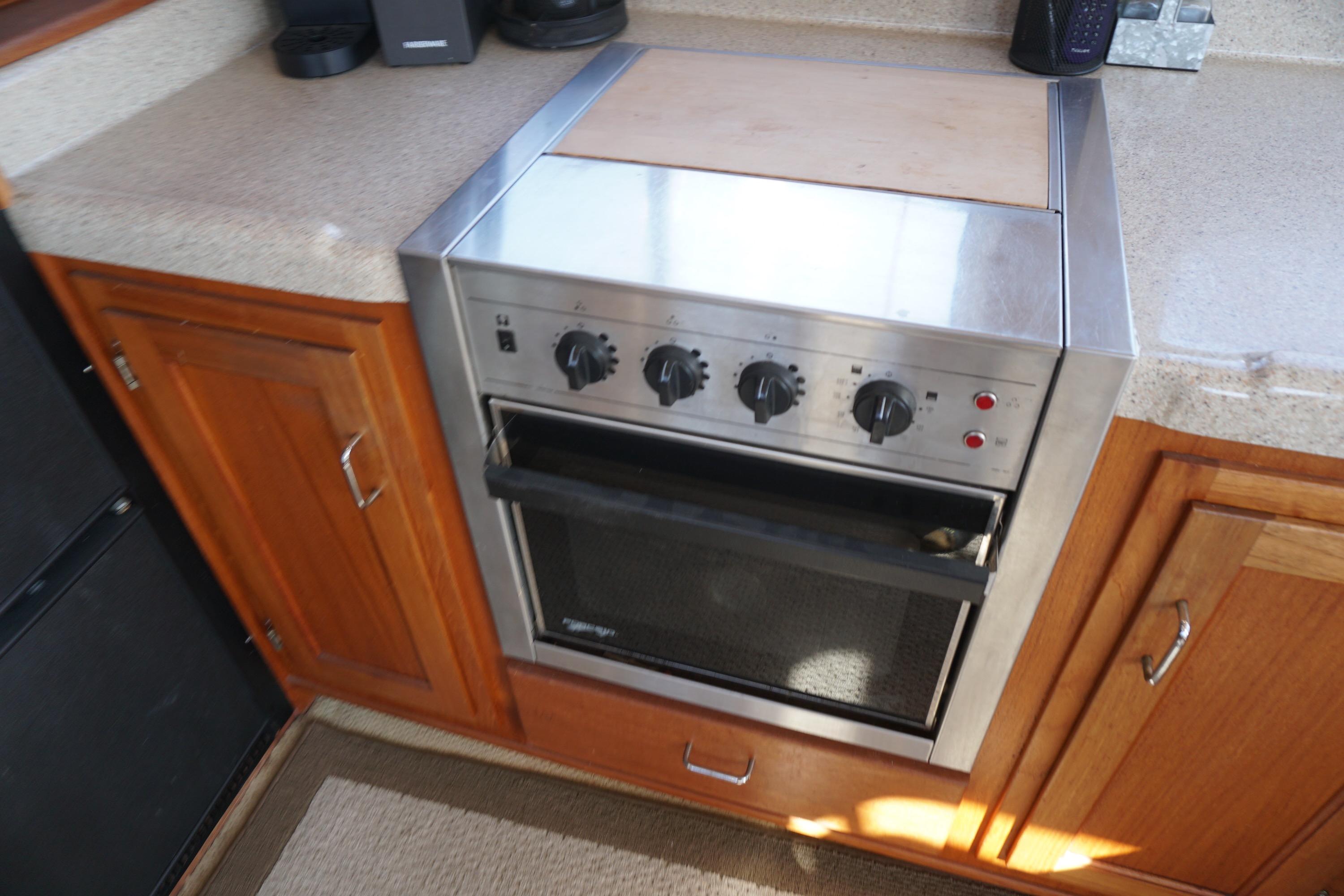 Stainless steel oven in 2004 American Tug 34 boat kitchen, surrounded by wooden cabinetry.