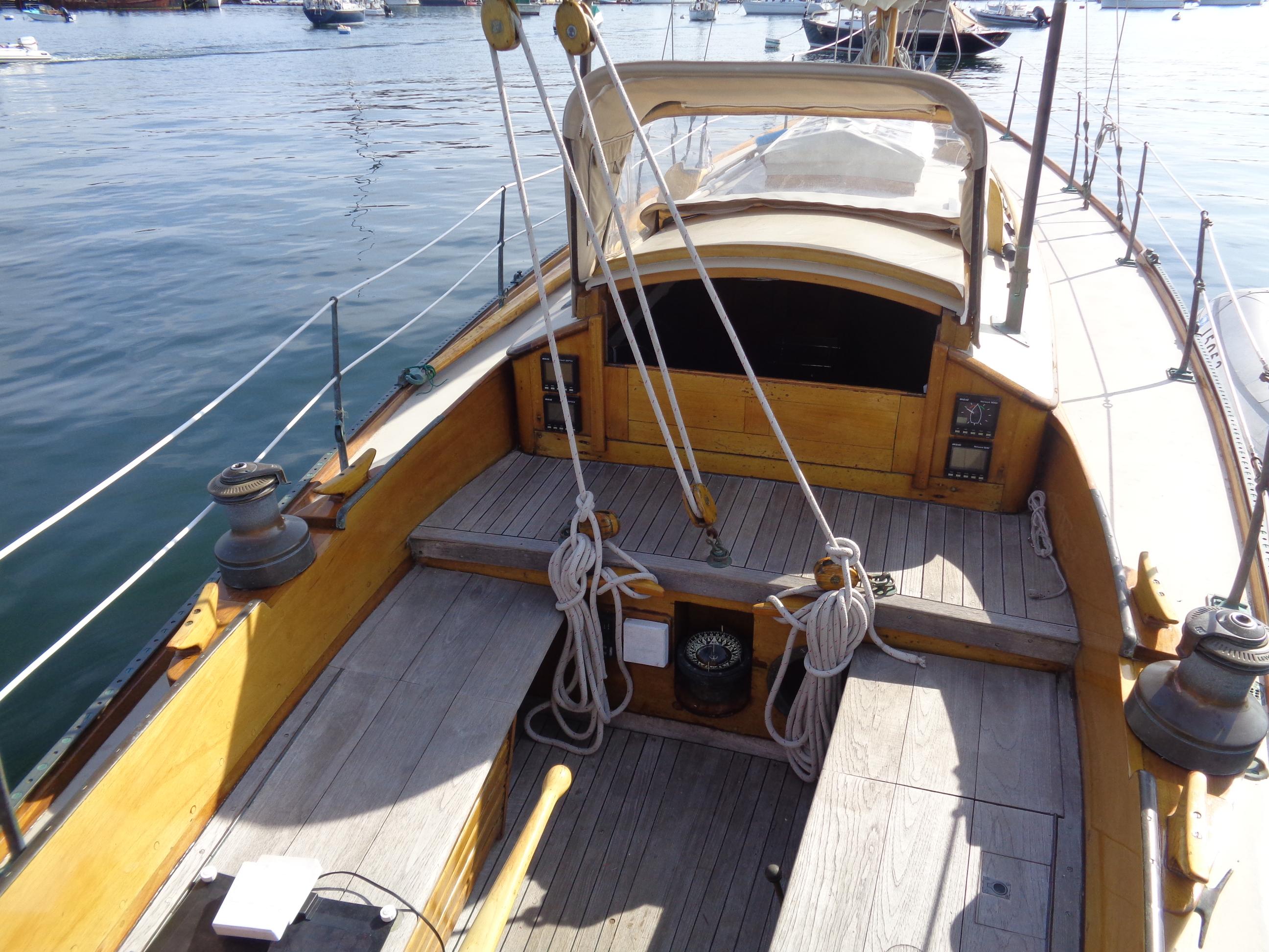 1960 Concordia 39 Yawl sailboat deck with wooden finish and rigging, docked on calm water.