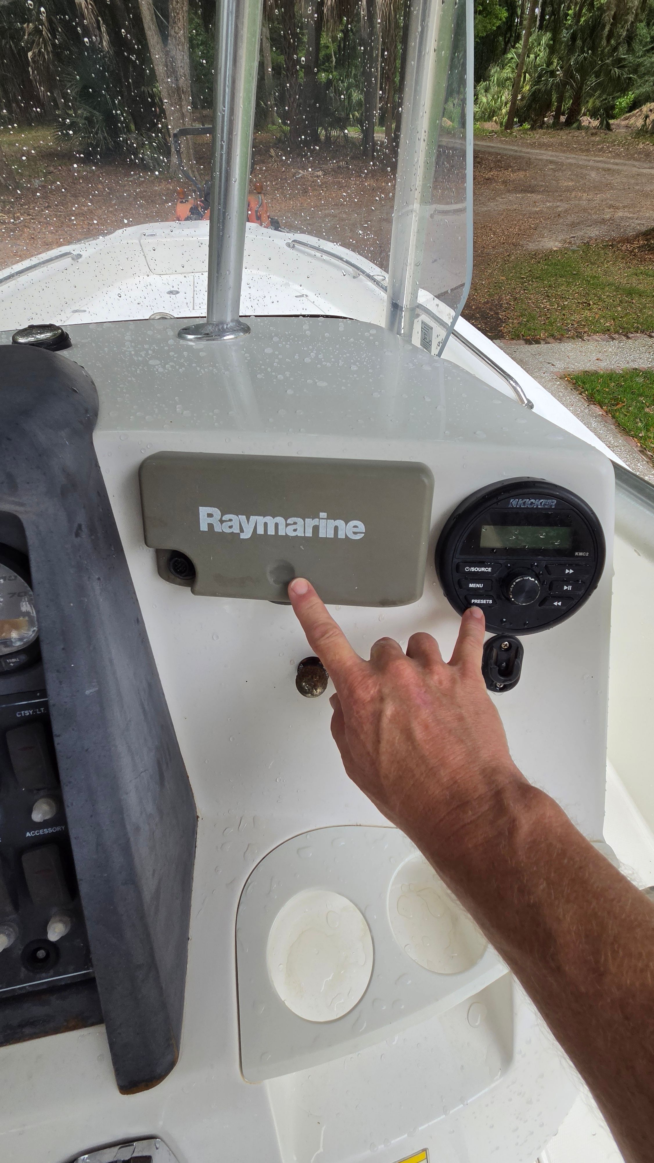 An arm points to a Raymarine device on the console of a Boston Whaler 230 Dauntless.