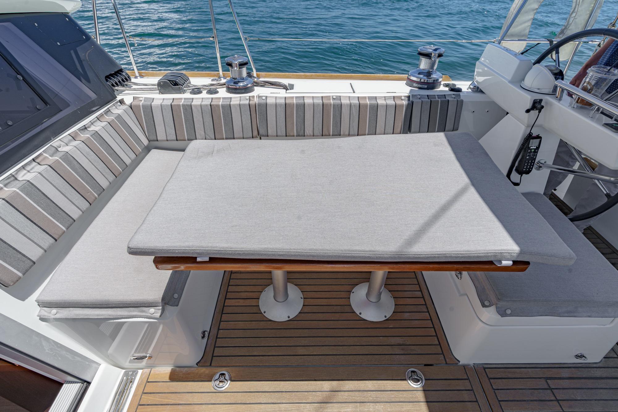 2017 Beneteau Sense 50 yacht cockpit with cushioned seating and table, overlooking the ocean.