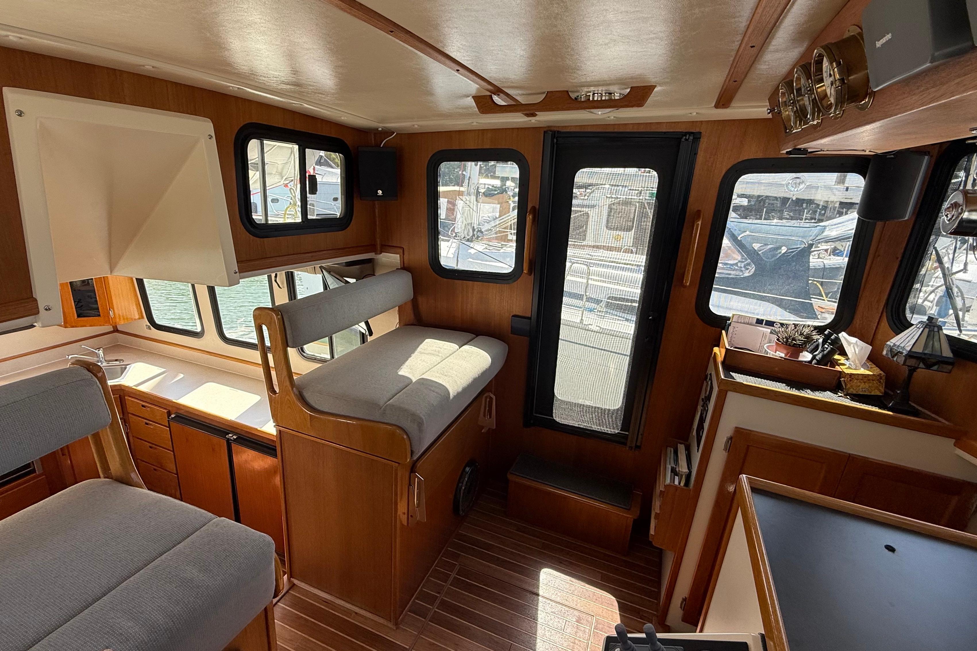 Interior of a 2002 Nordic Tug 32 boat, featuring wood paneling and seating.