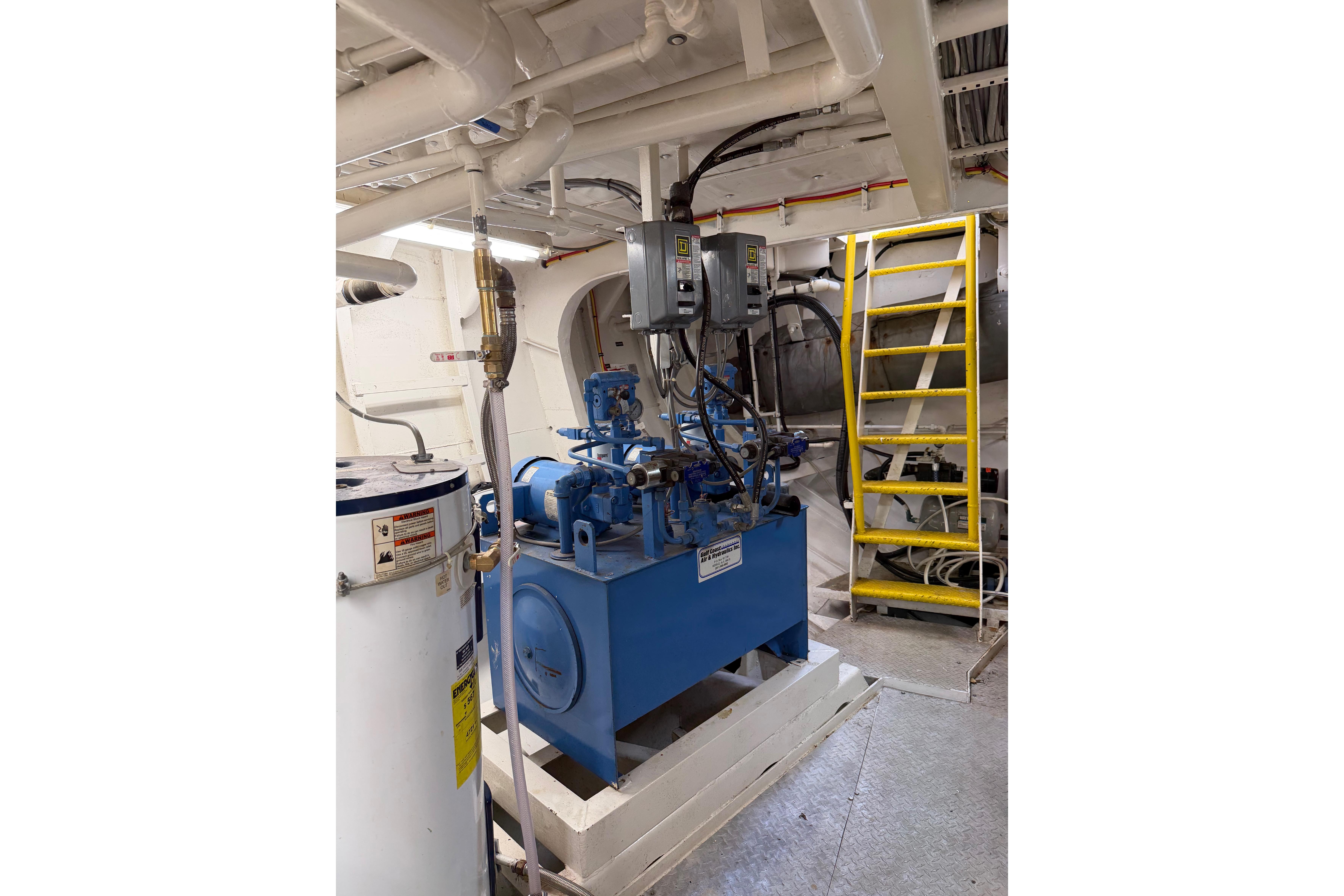 Engine room of a 1954 American 70 Tugboat with machinery and yellow ladder.