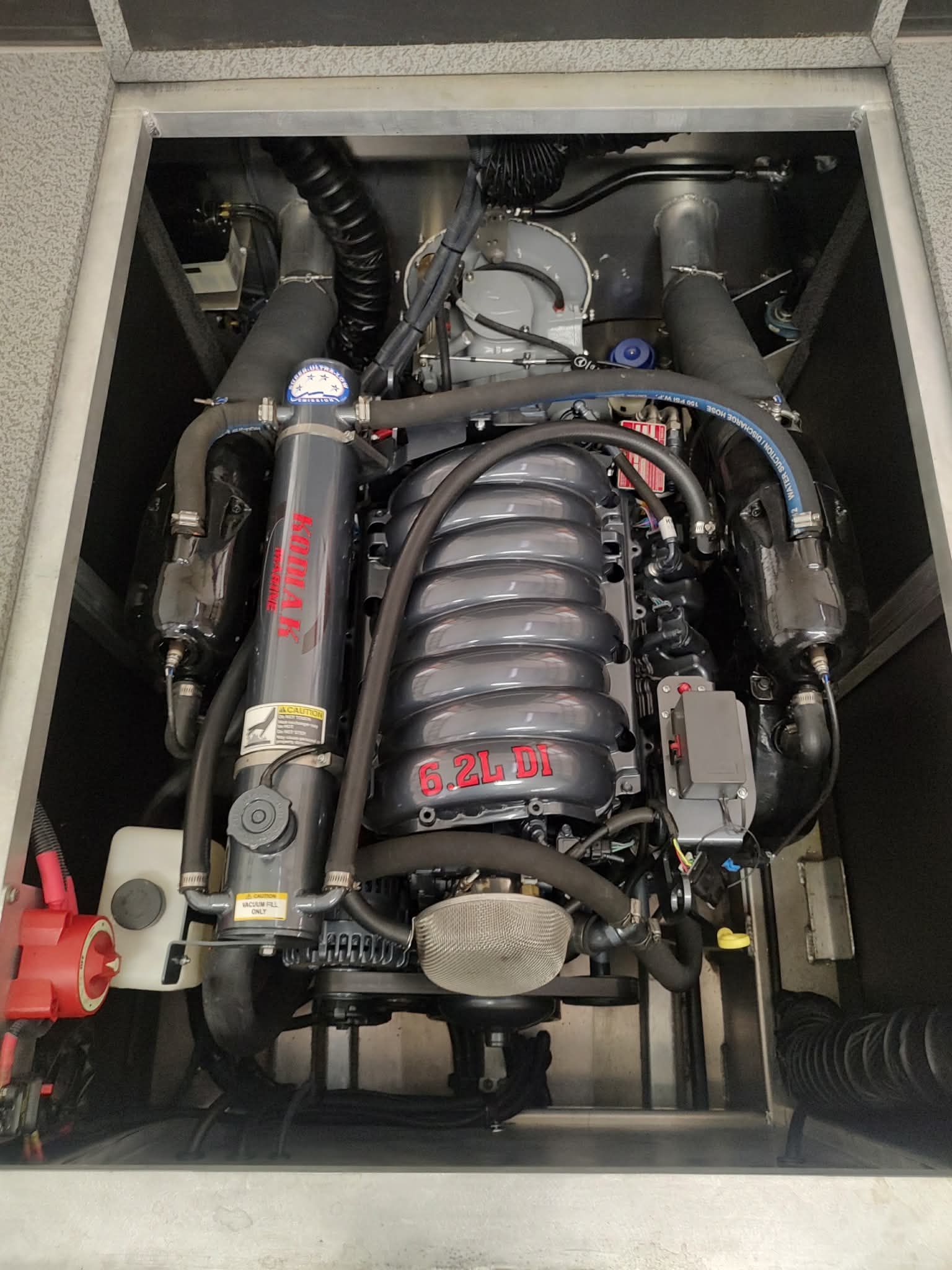 A powerful 6.2L engine is mounted inside a boat, surrounded by hoses and cables.
