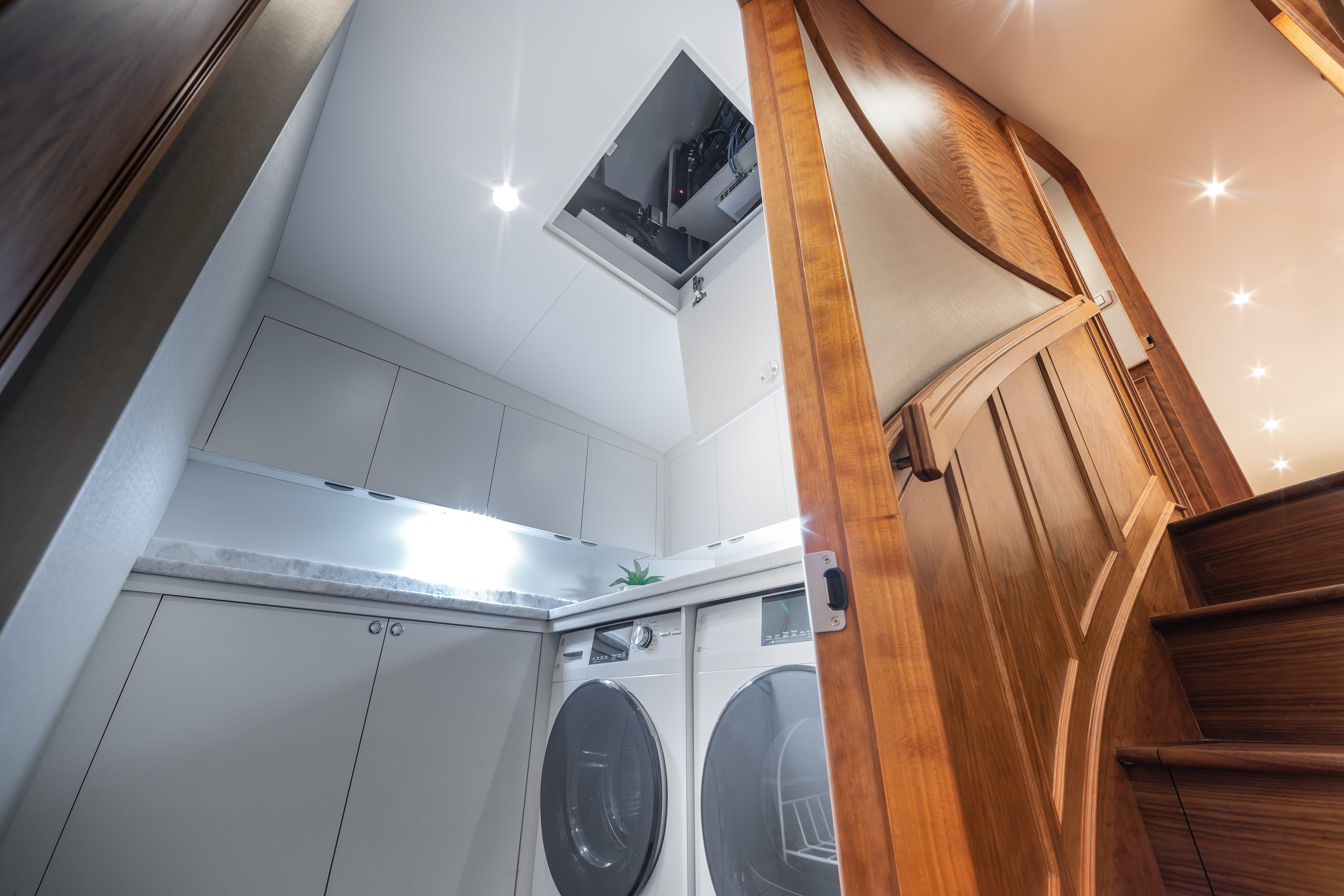 Laundry area inside a 2020 Jarrett Bay 84 yacht, featuring modern appliances and wooden cabinetry.