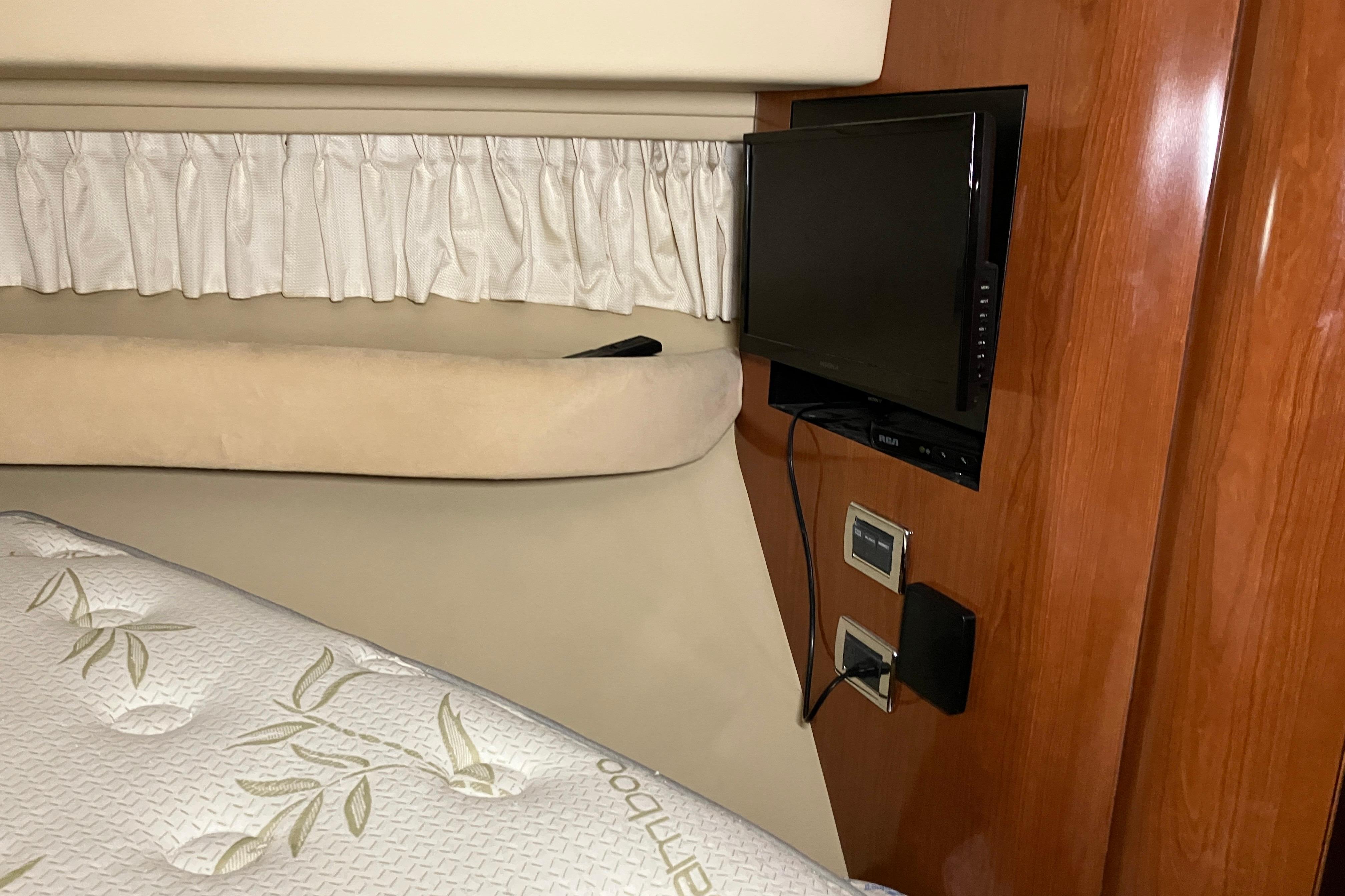 Interior of 2002 Sea Ray 410 Sundancer with TV, bed, and wooden paneling.