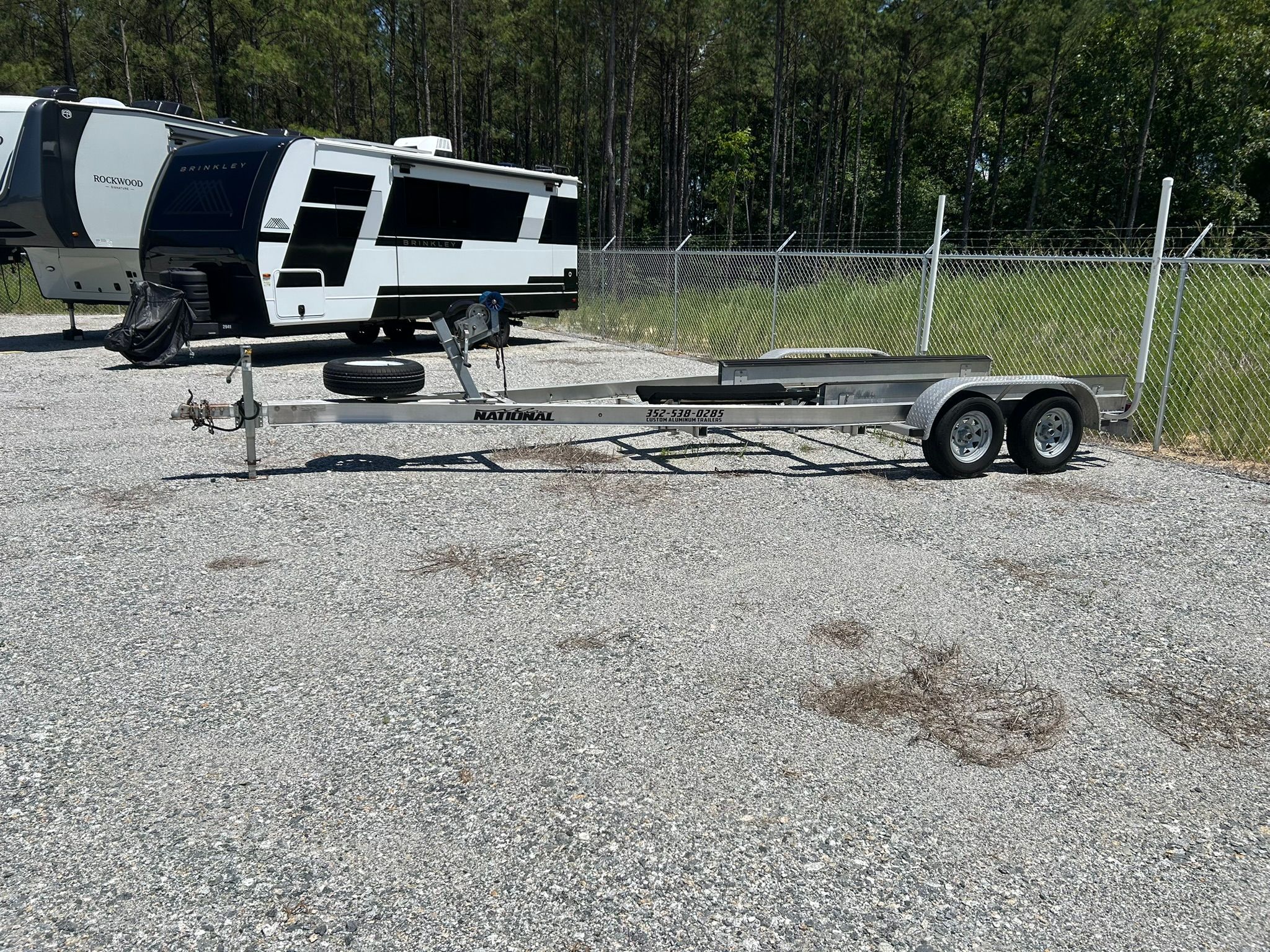 Boat trailer on gravel lot next to RVs.