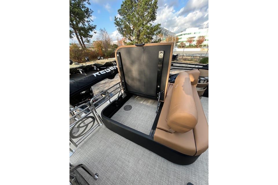 2025 Regency 230 LE3 Sport boat interior with open storage compartment and tan seating.