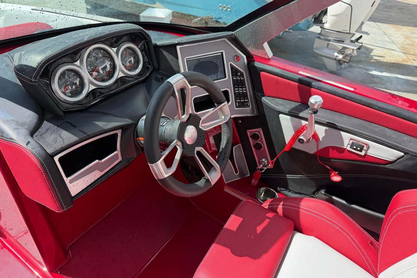 2023 MasterCraft X24 boat interior with red upholstery and modern dashboard controls.