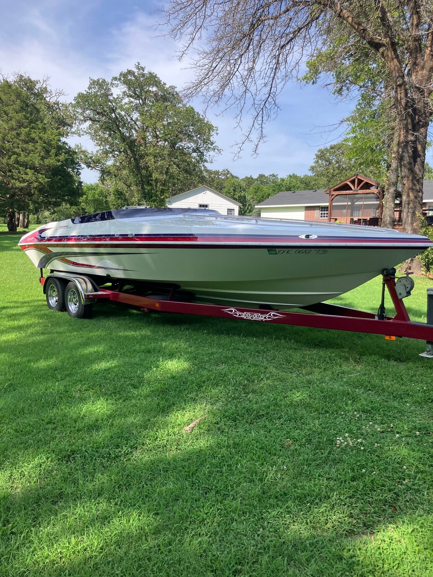 A 2003 Howard Bullet boat on a trailer sits on a green lawn.