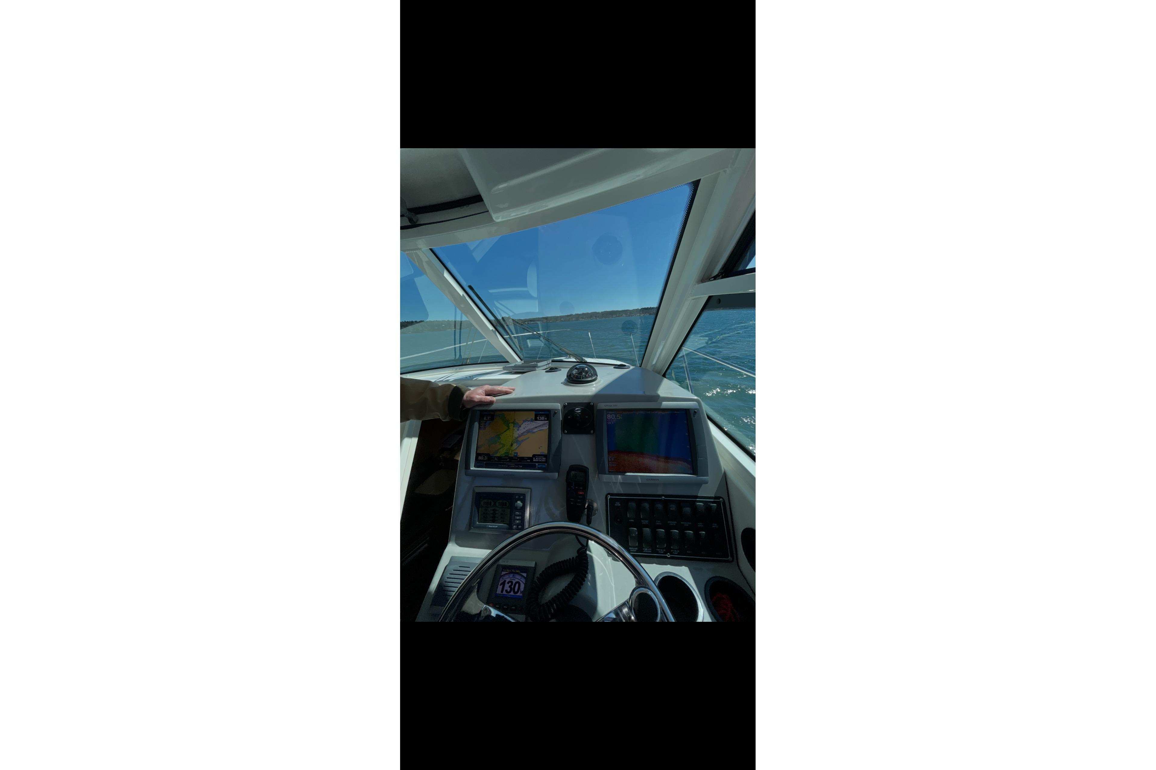 Cockpit view of 2013 Boston Whaler 315 Conquest with navigation screens and steering wheel.