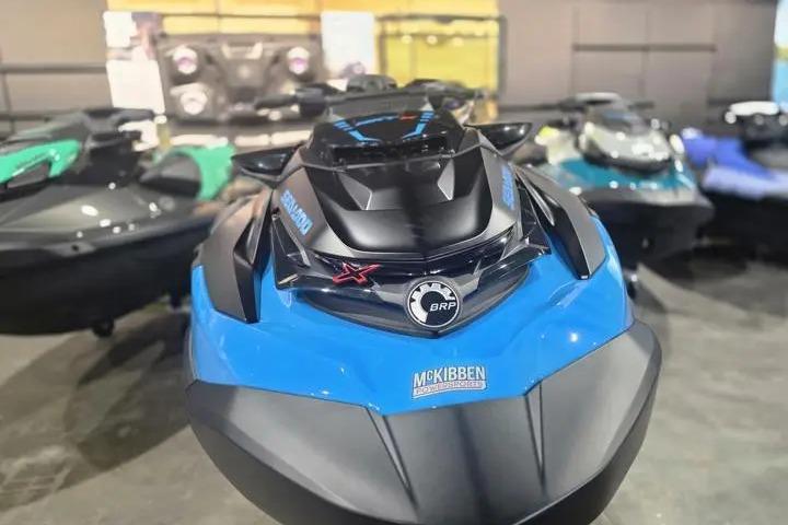 2026 Sea-Doo RXT-X 325 jet ski in showroom, front view, blue and black design.