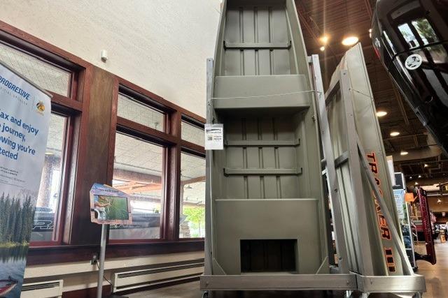 2026 Tracker Grizzly 14 Jon boat displayed in a showroom with promotional materials.