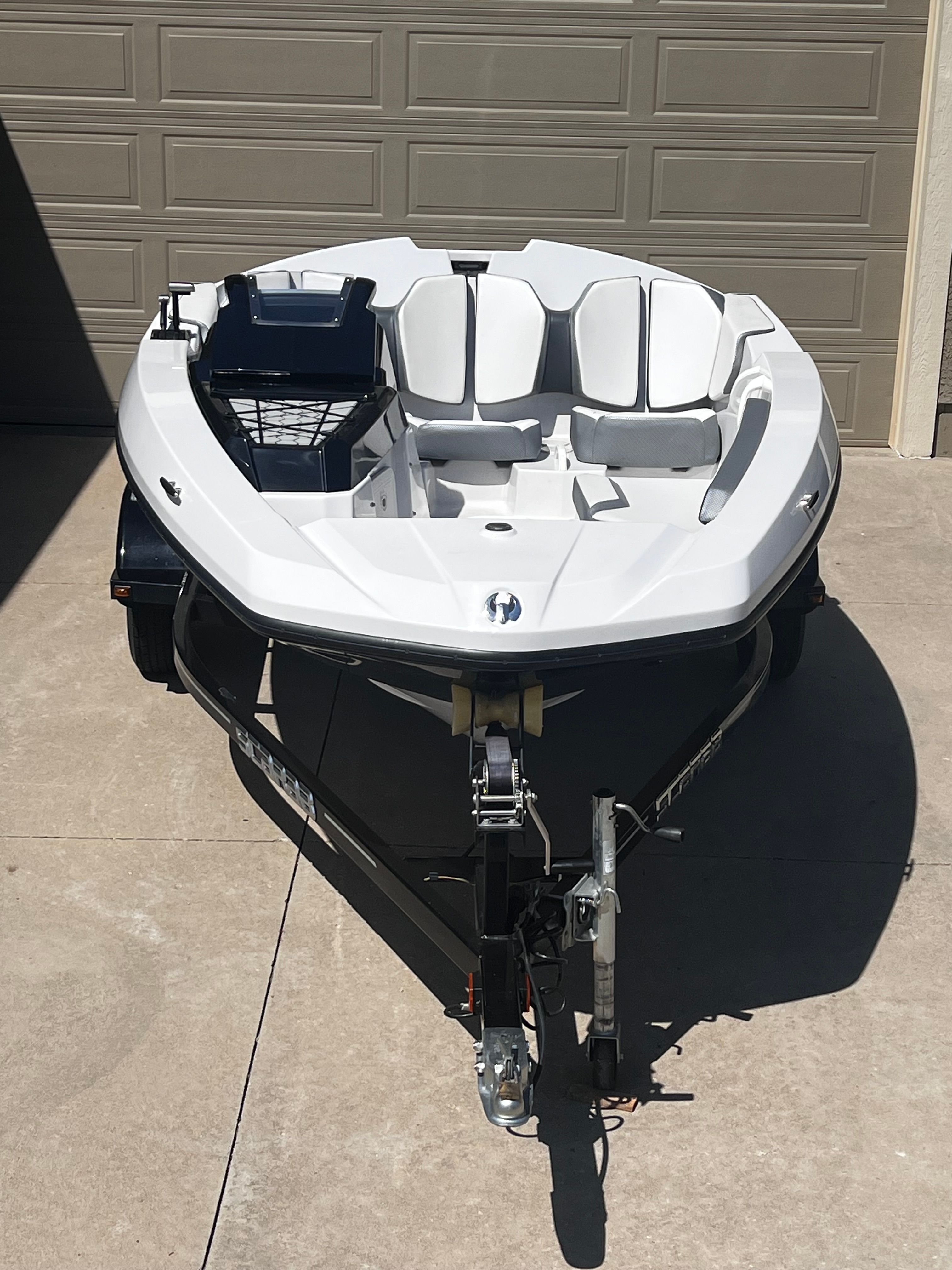 A white Scarab 165 G boat is on a trailer in a driveway.