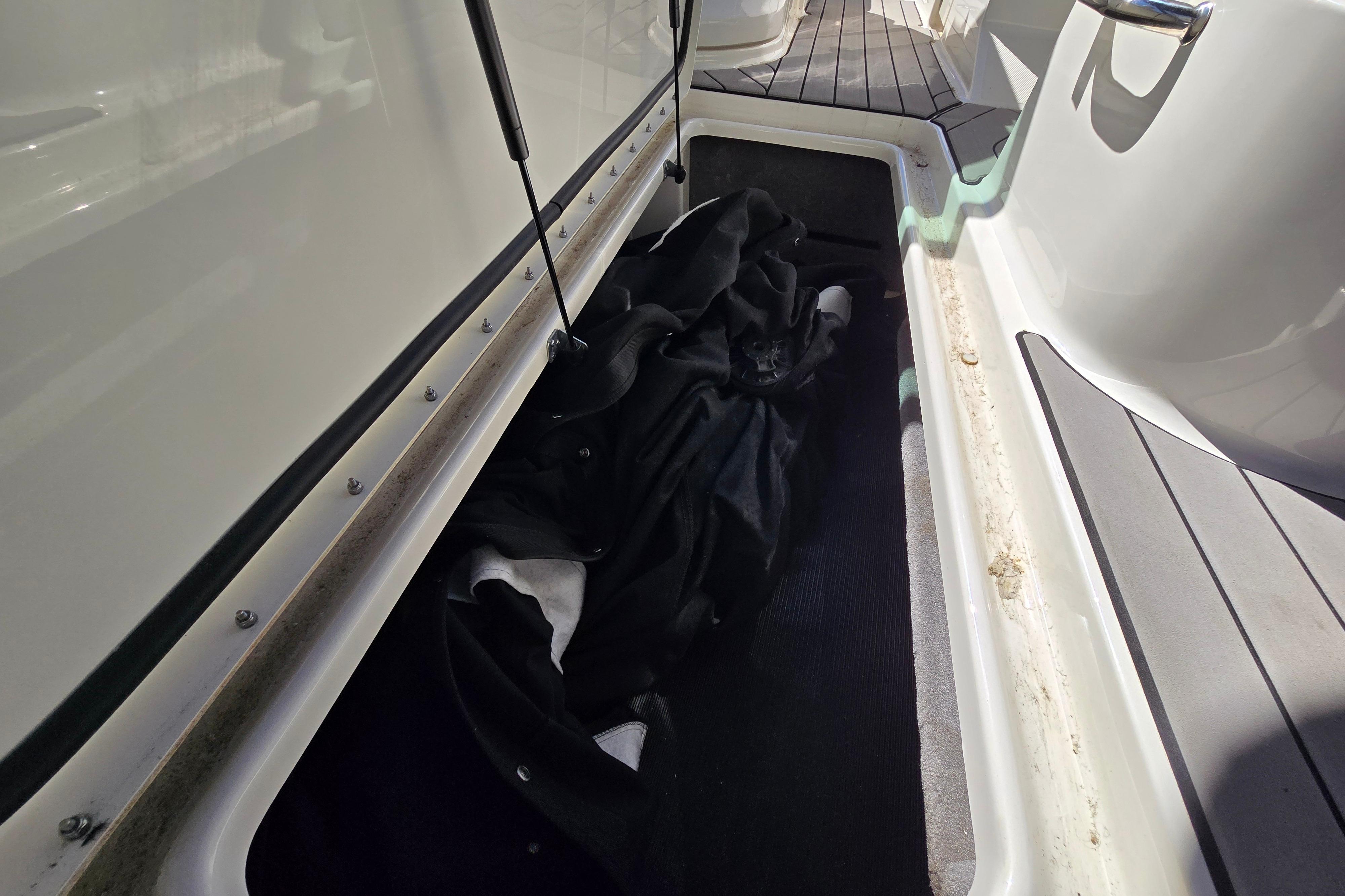 Storage compartment on a 2022 Sea Ray SLX 280 boat, featuring a black cover.