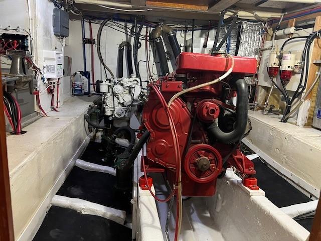 Engine room of 1981 Island Trader 46 with red and white engines, wiring, and equipment.