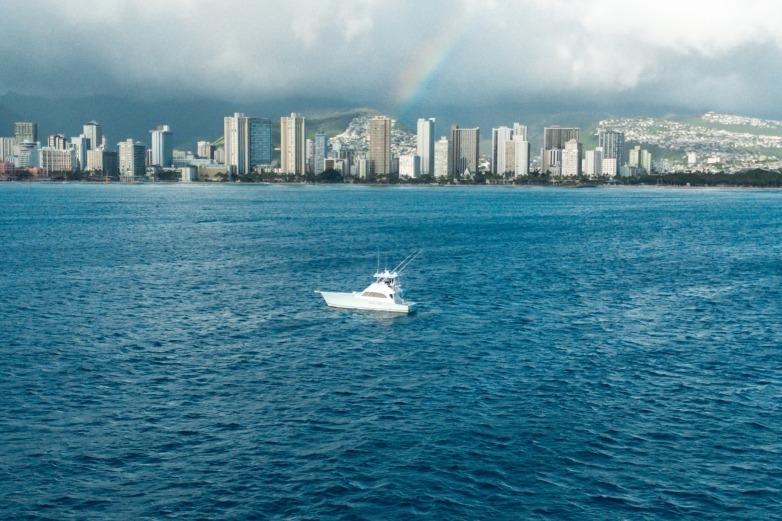 Boat on ocean with city skyline and rainbow in background, Post 50 model, 1998.