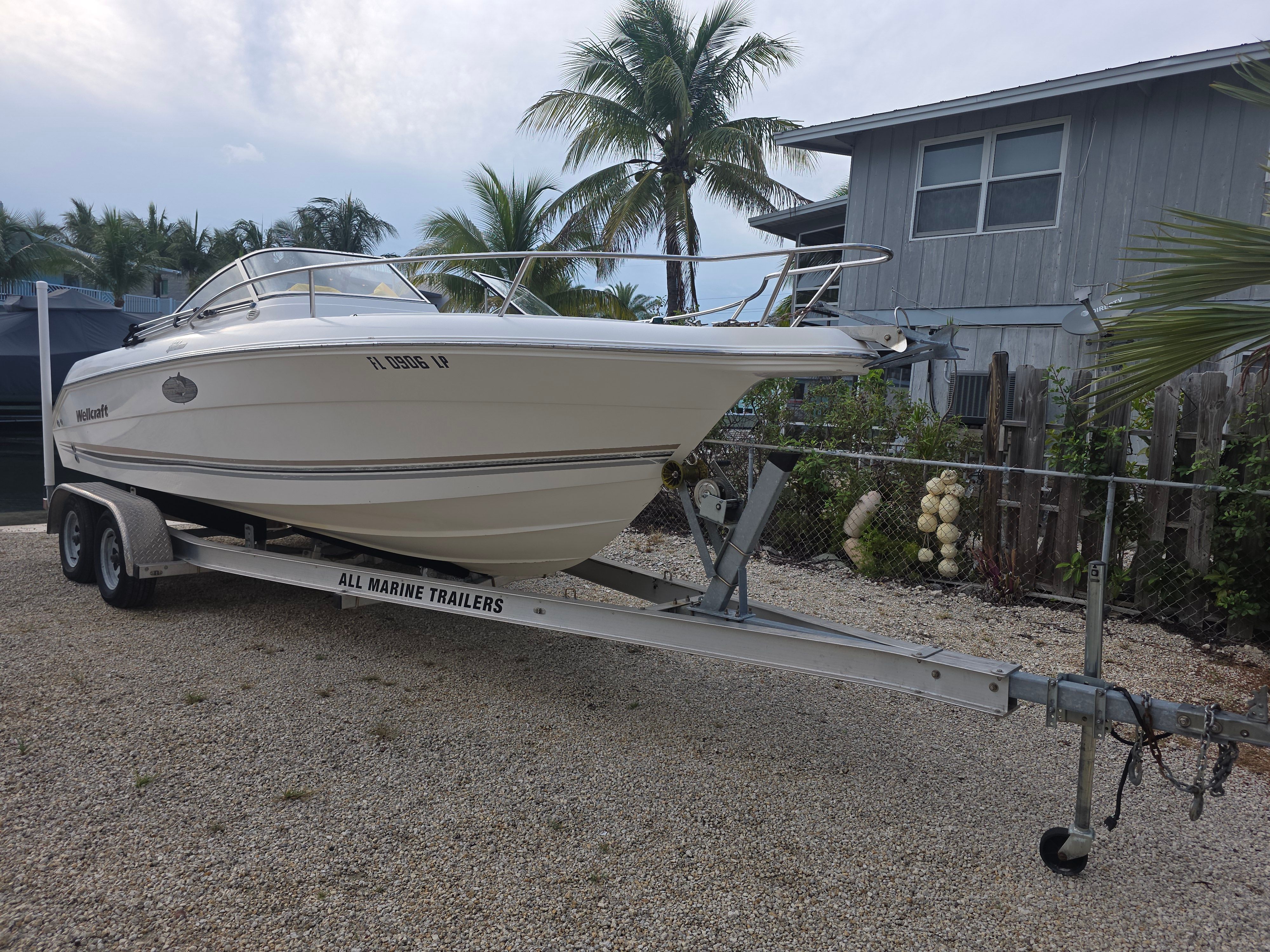 2001 Wellcraft Sportsman on trailer in front of tropical house.
