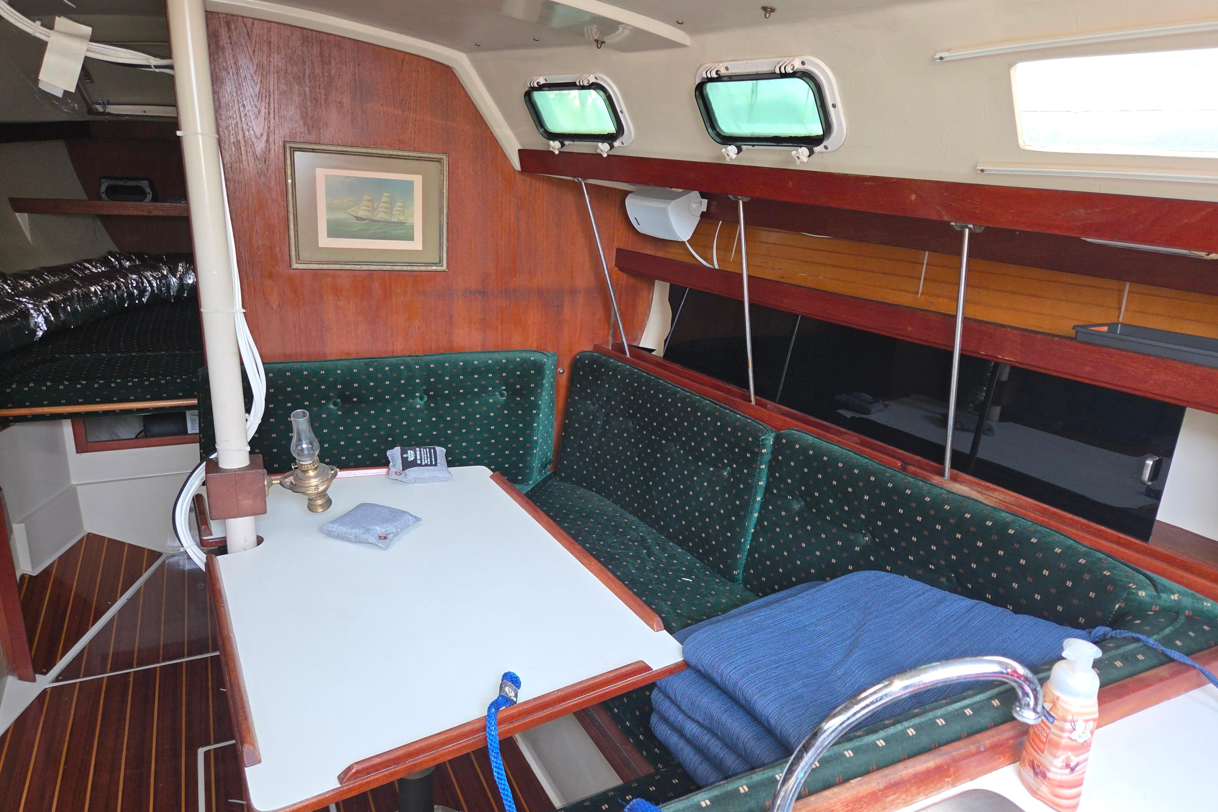 Interior of a 1986 Catalina 355 sailboat with green upholstery and wooden accents.