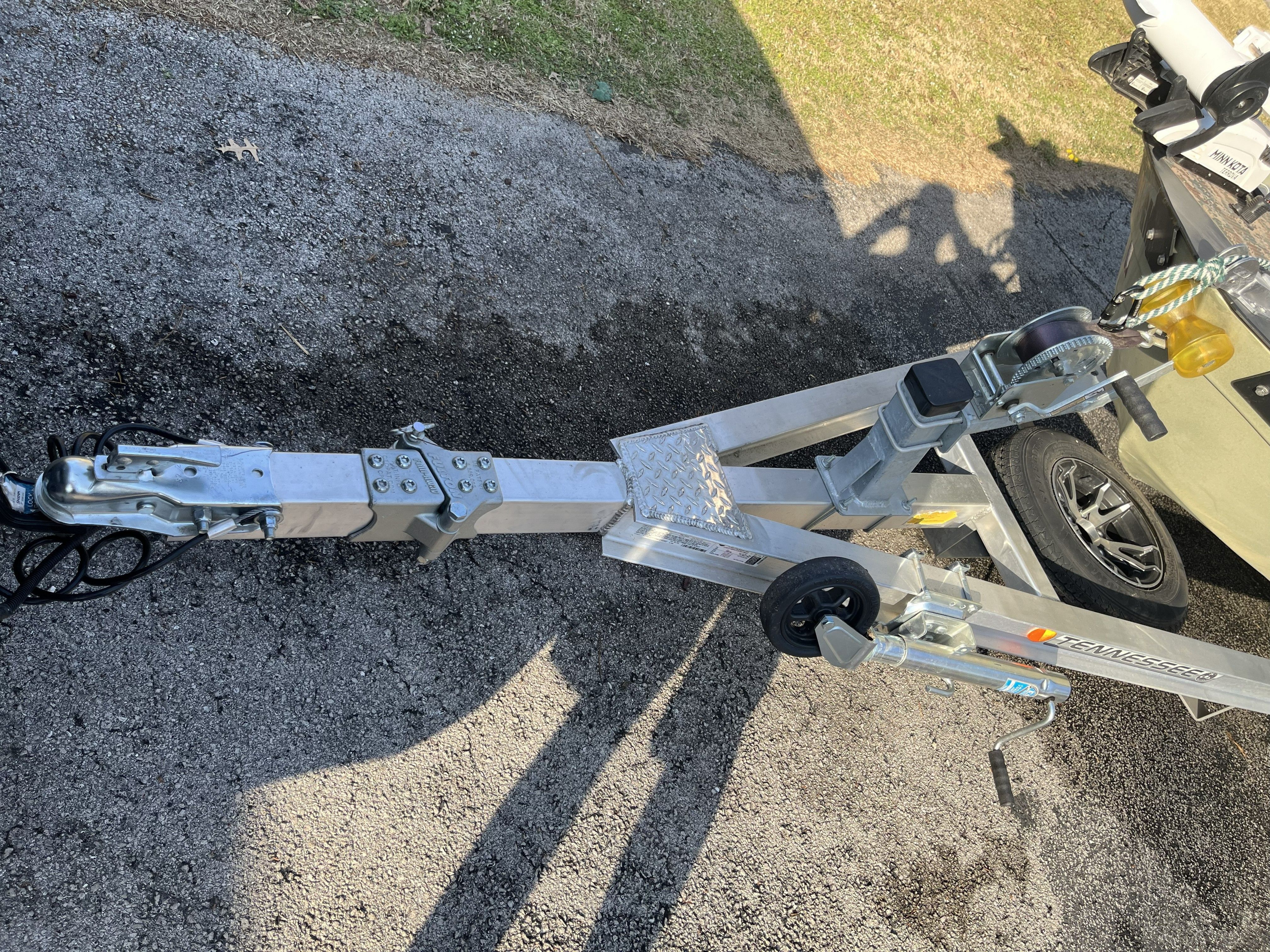 Boat trailer with winch and hitch on asphalt.
