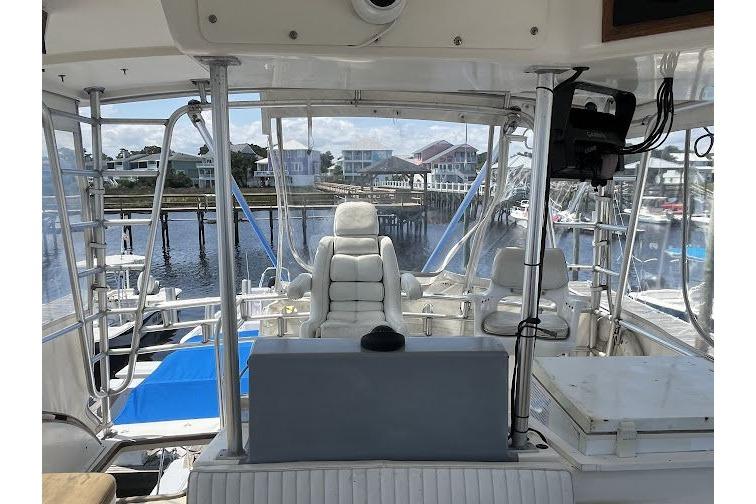 1989 Topaz 44 Sportfisherman boat interior with marina view, featuring white seating and control panel.