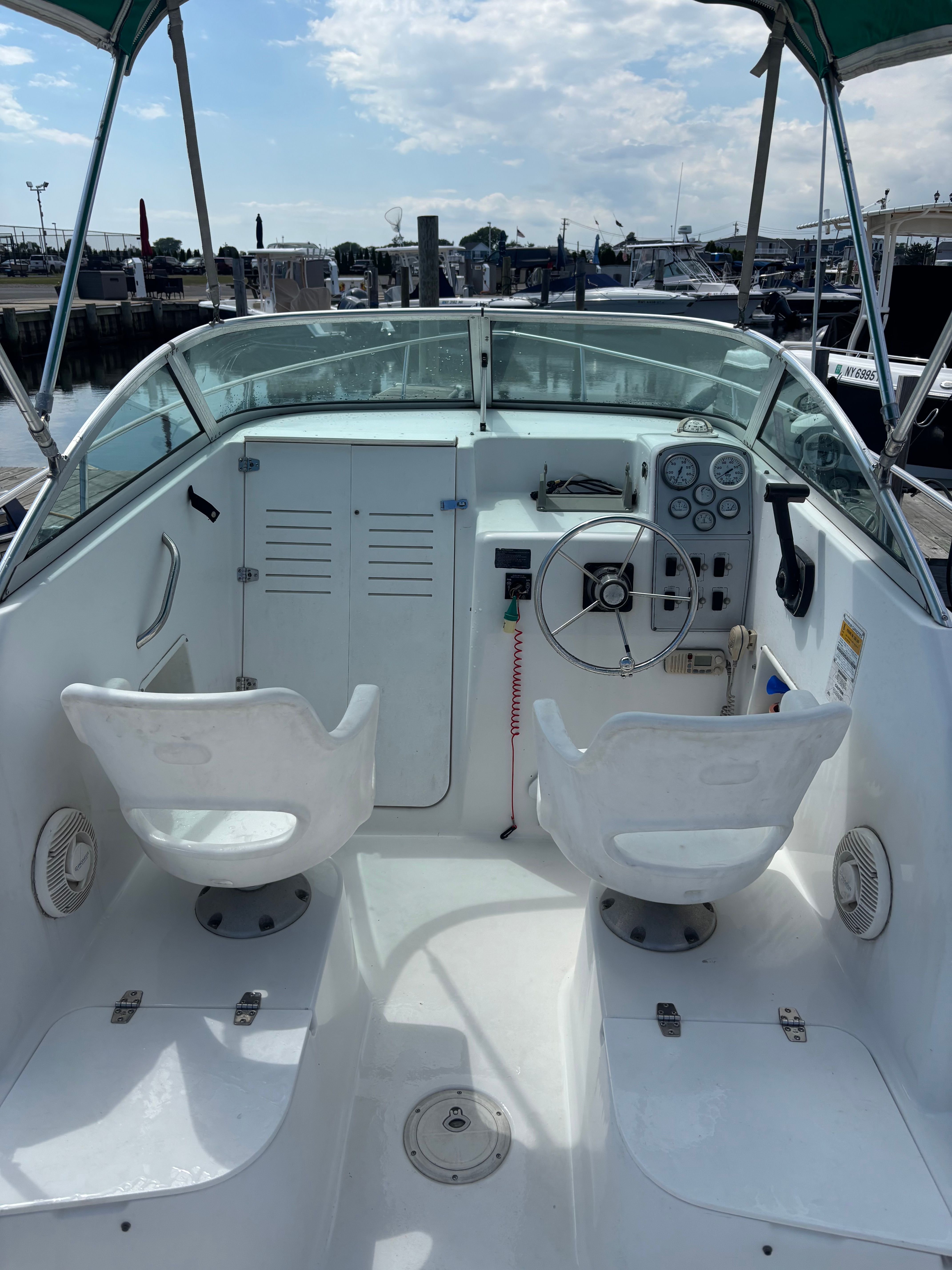 The image shows the cockpit of a 1999 Pro-Line 221 Walk Around boat with two white seats.