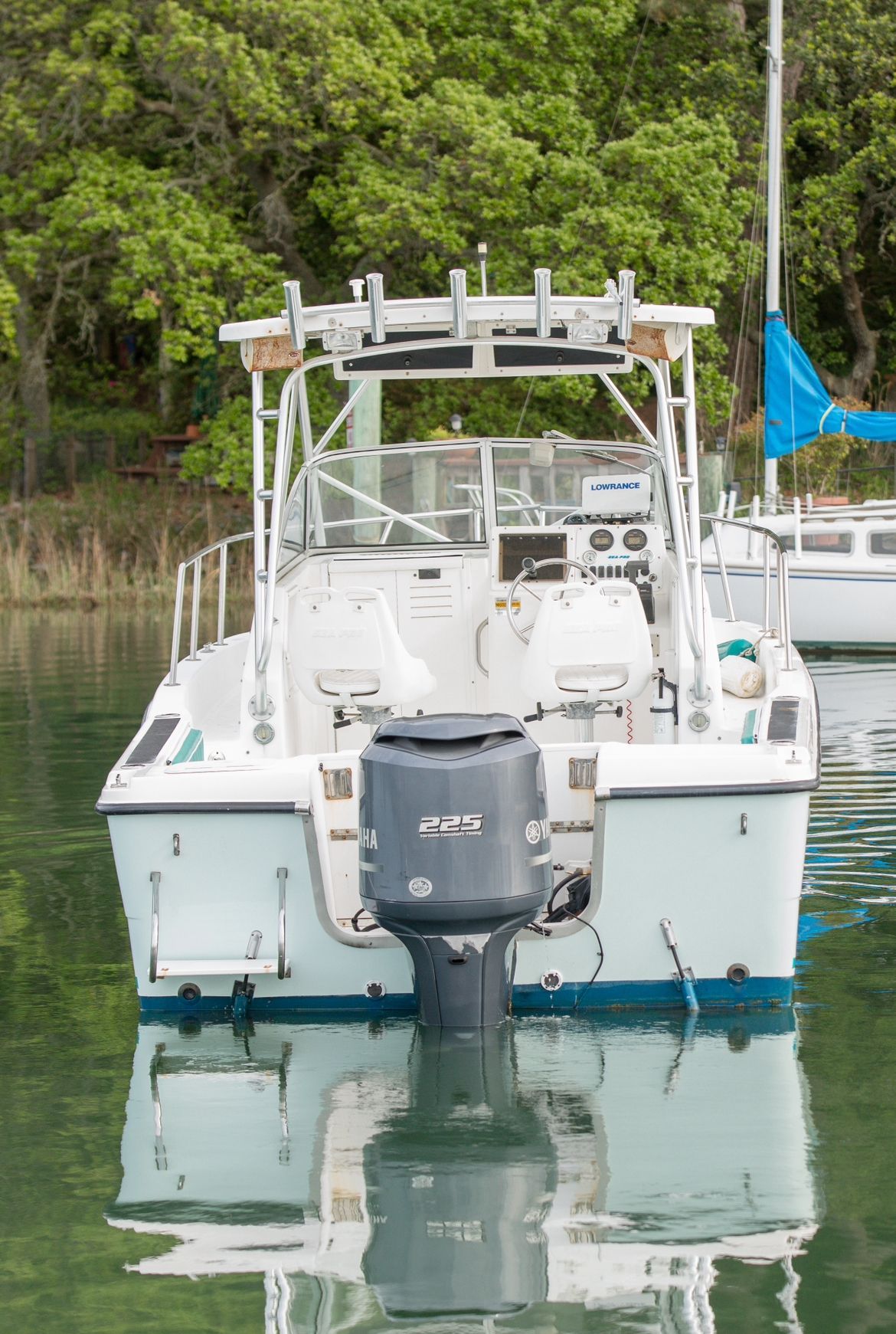 A 2002 Sea Pro WA235 boat with an outboard motor, anchored on calm water.