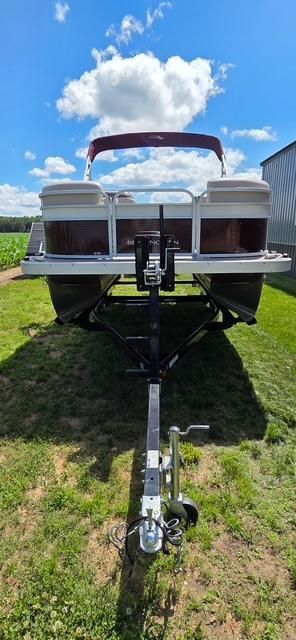 A 2018 Bennington 18SL pontoon boat on a trailer, set on a grassy area.