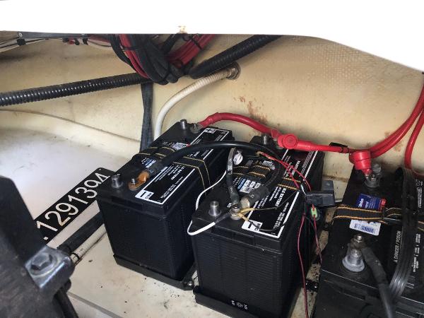 Batteries in a boat's engine compartment, with cables and hoses.
