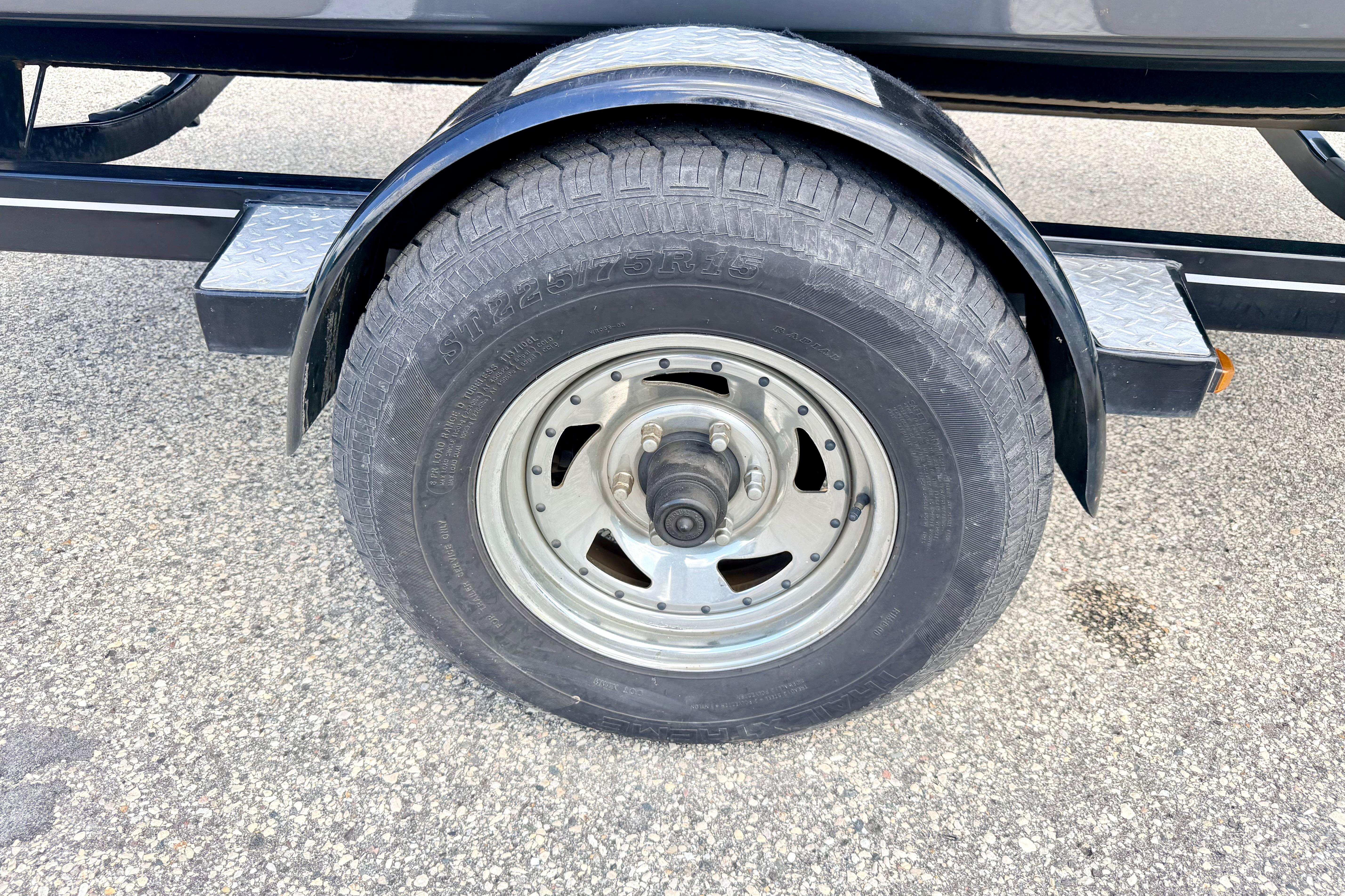 Trailer wheel of a 2018 Glastron GT 185 on asphalt surface.