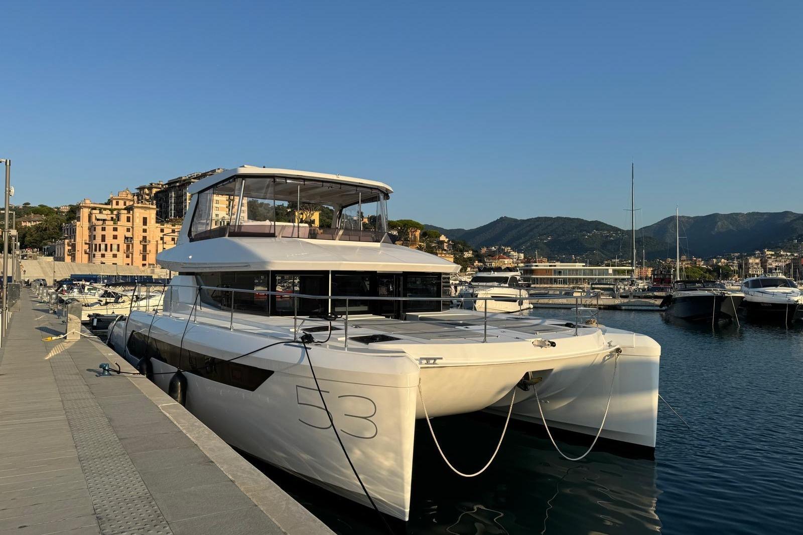 2024 Leopard 53 Powercat yacht docked in a scenic marina with mountains in the background.