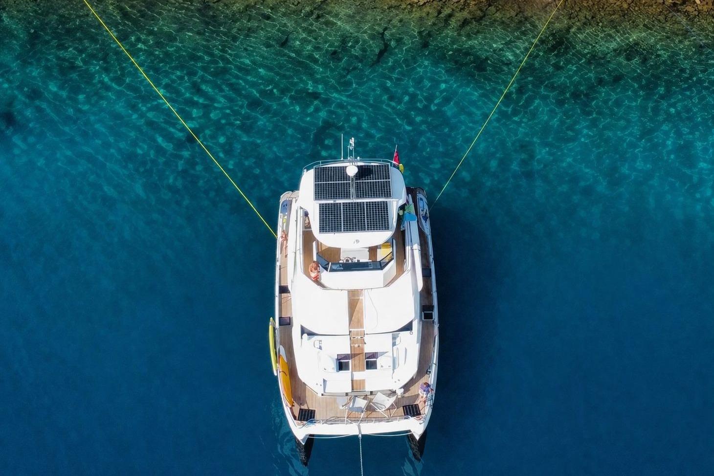 Aquila 54 Yacht 2021 anchored in clear blue water, aerial view.