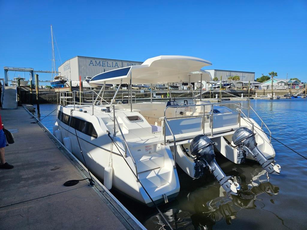 Modern Smart Cat M280 Power catamaran docked at marina, featuring dual outboard engines.