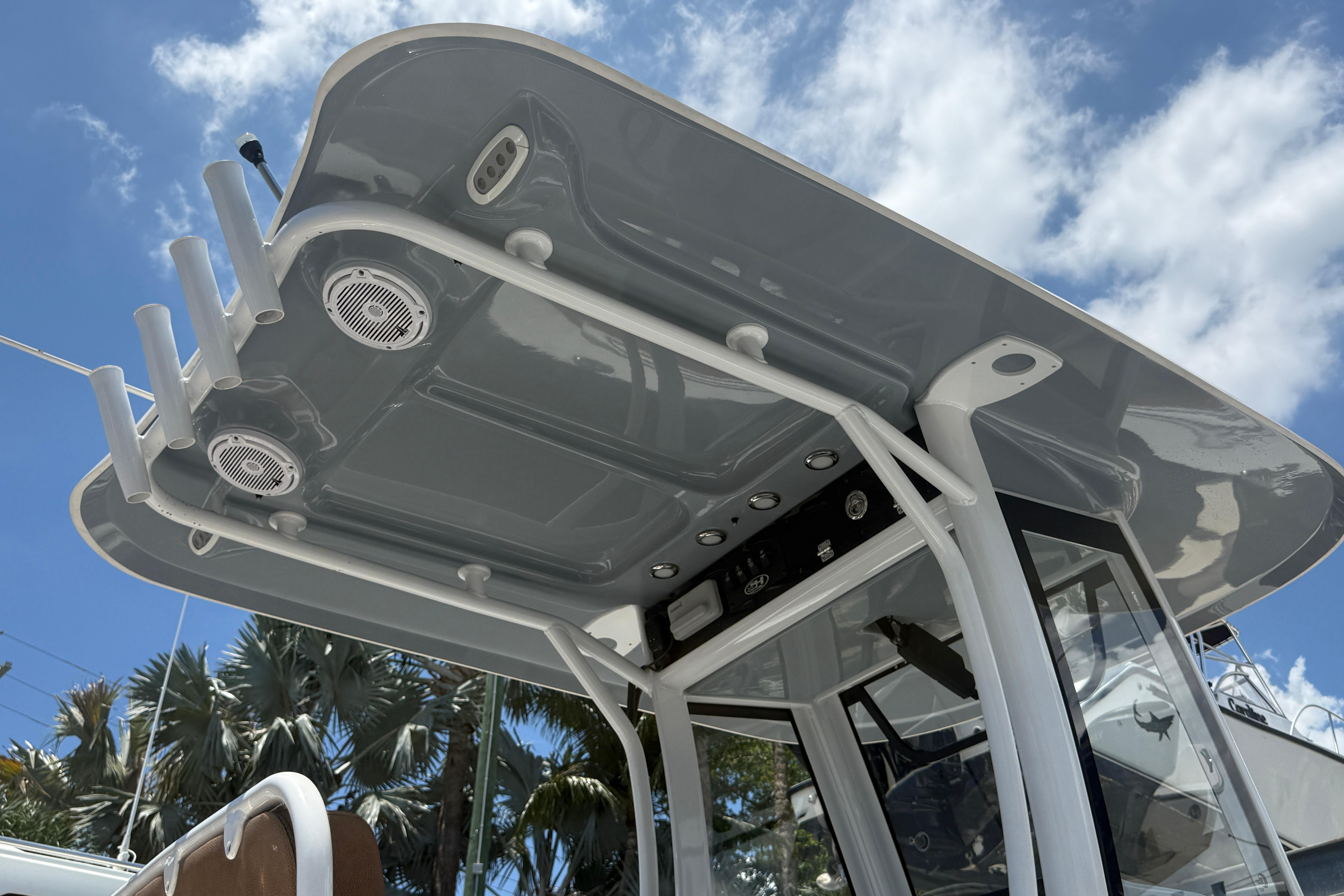 2020 Sea Hunt Ultra 275 SE boat canopy with speakers and rod holders under blue sky.