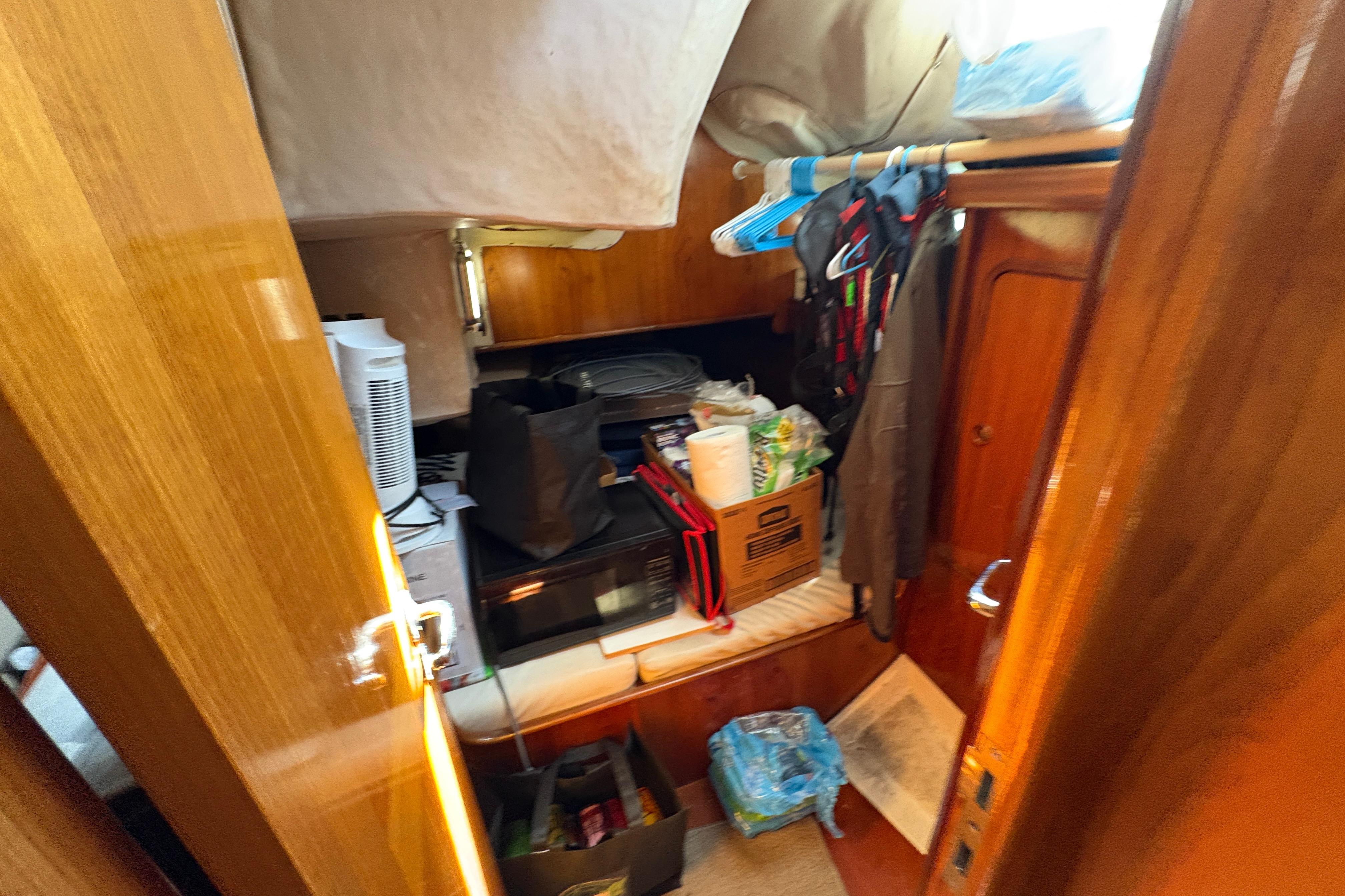 Interior of 1990 Beneteau Oceanis 500 sailboat with storage and hanging clothes.