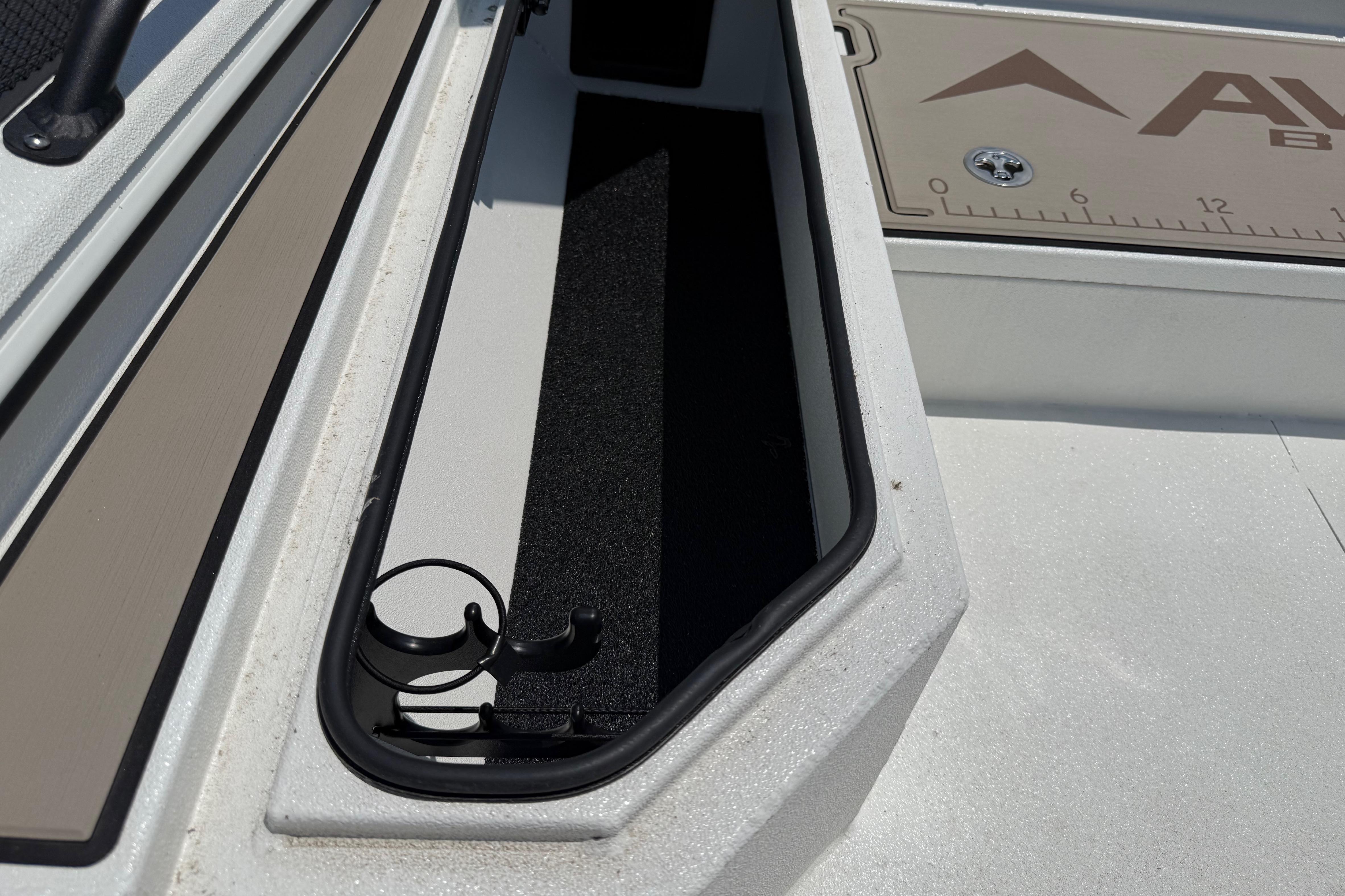 2025 Avid 22 Recon boat storage compartment with rod holders and measuring board.
