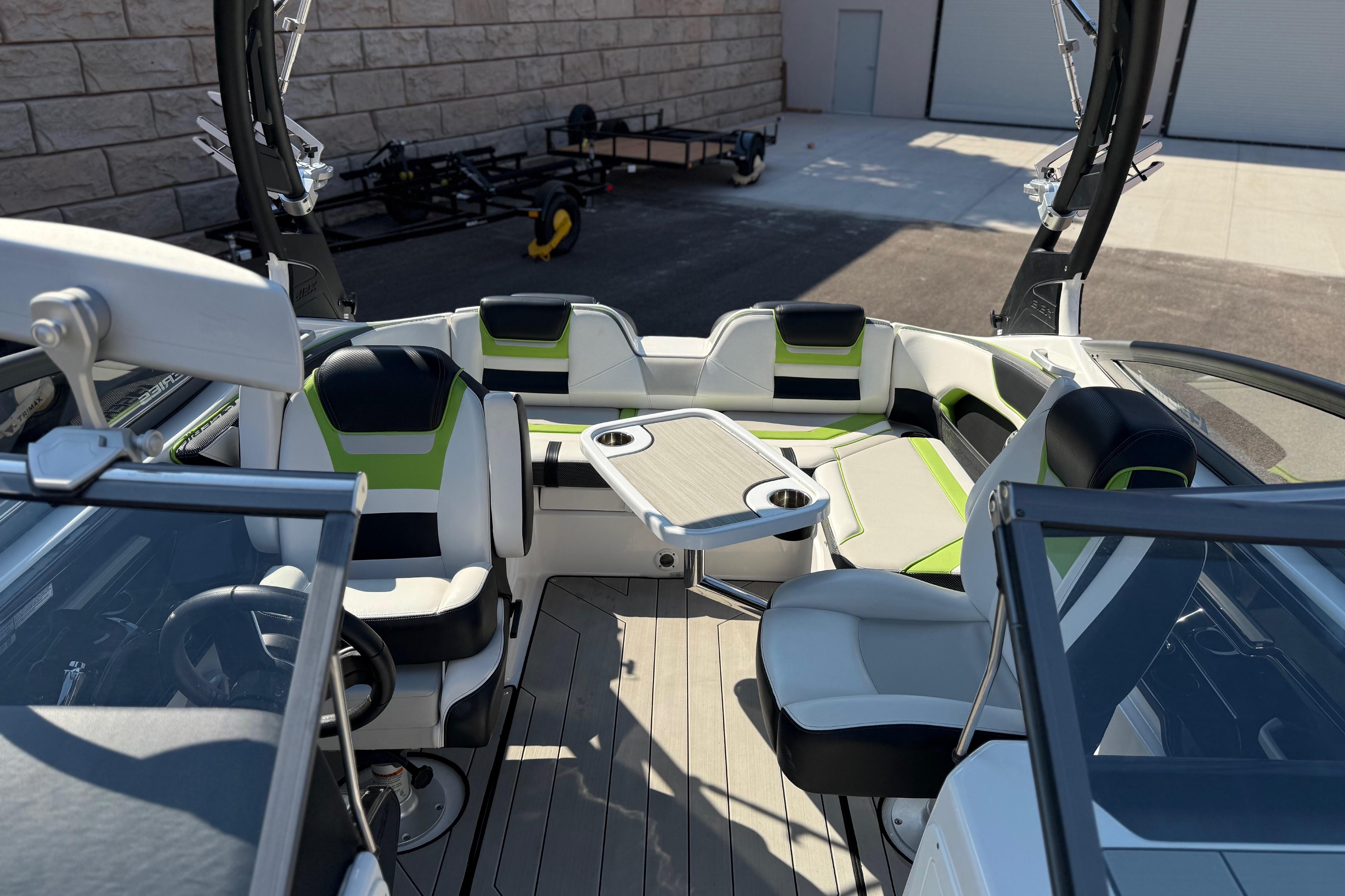 2022 Yamaha Boats 212XE interior with modern seating and table, docked outdoors.