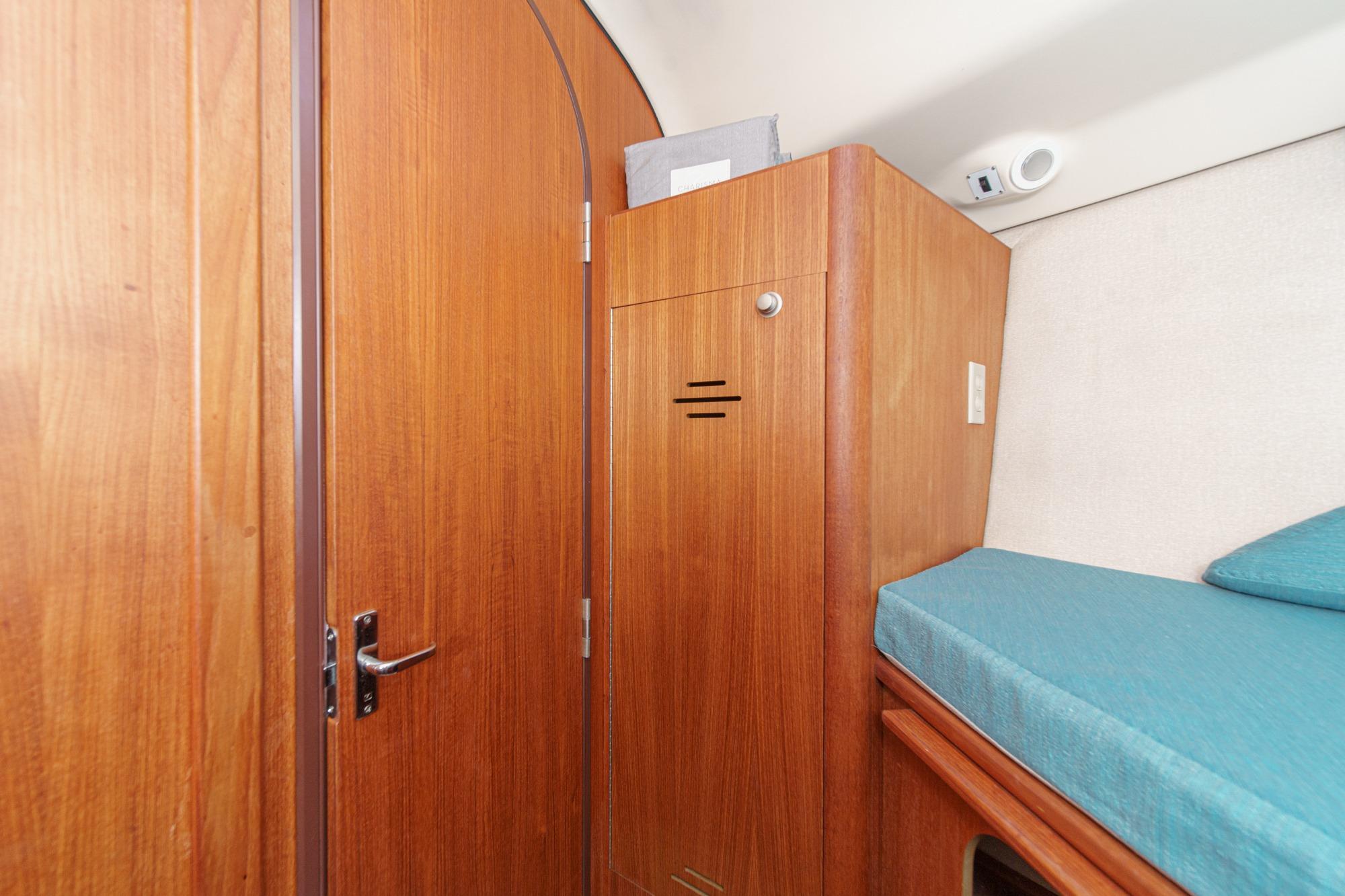 Wooden interior of 1996 Hunter 376 sailboat with storage and blue cushioned seating.