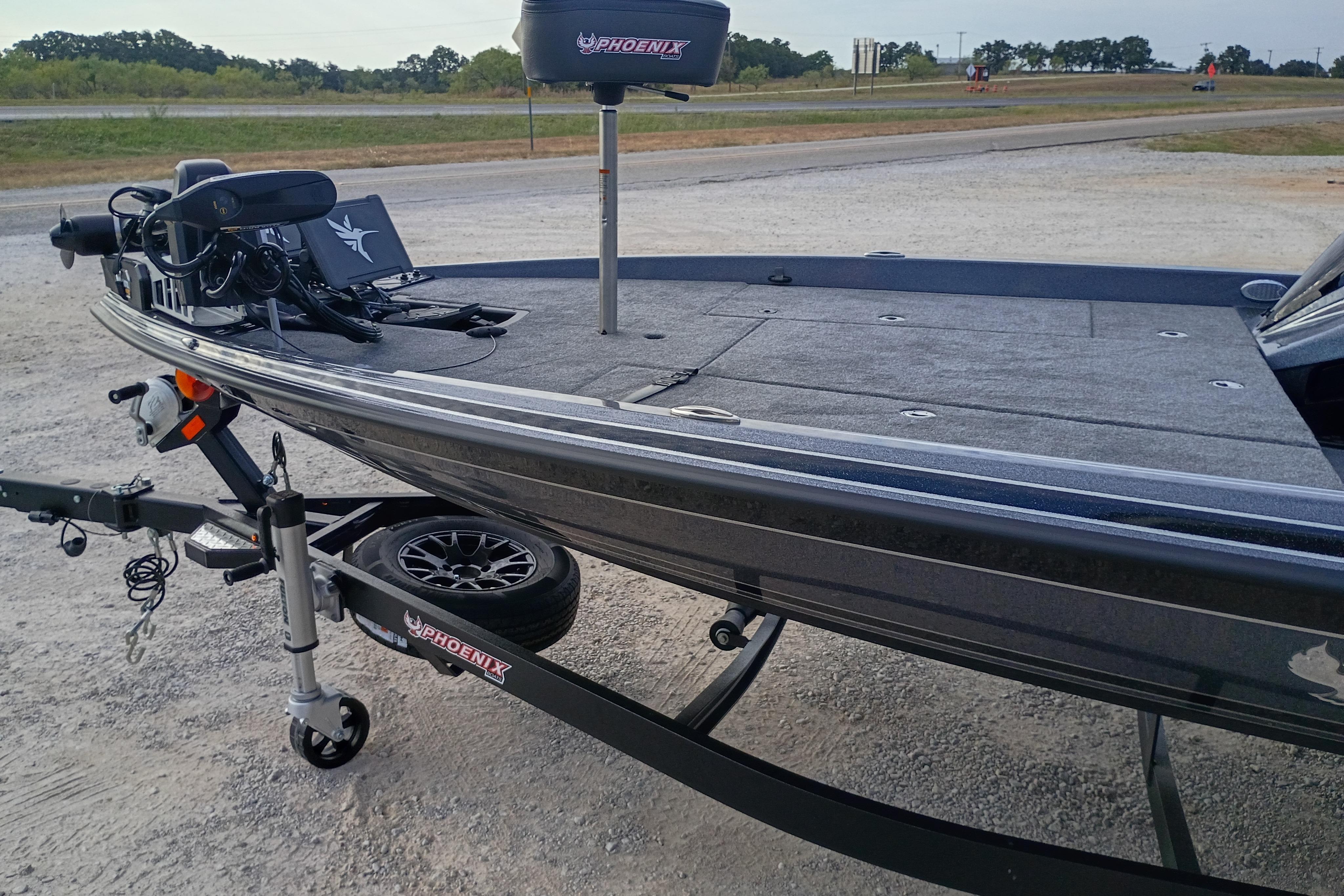 2026 Phoenix 921 ELITEX boat on trailer, parked on gravel near highway.