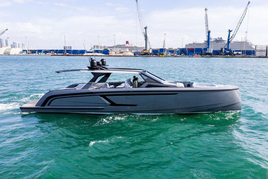 2024 Vanquish Yachts VQ55 cruising in a harbor with cranes and ships in the background.
