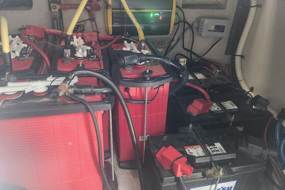 Battery compartment of a 2005 Sea Ray 390 Sundancer with multiple red and black batteries.