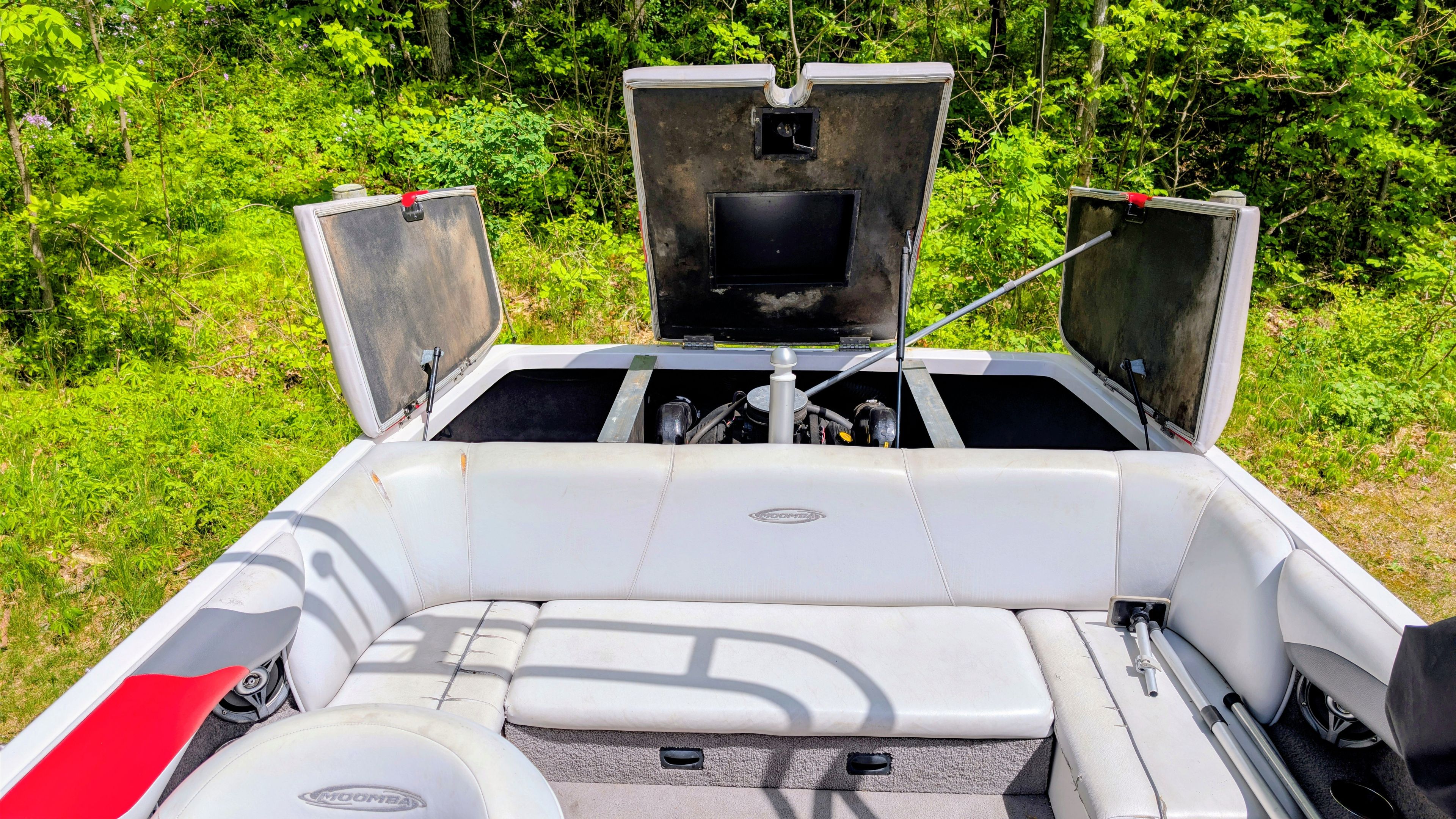 2007 Moomba Outback V boat with open engine compartment in greenery.