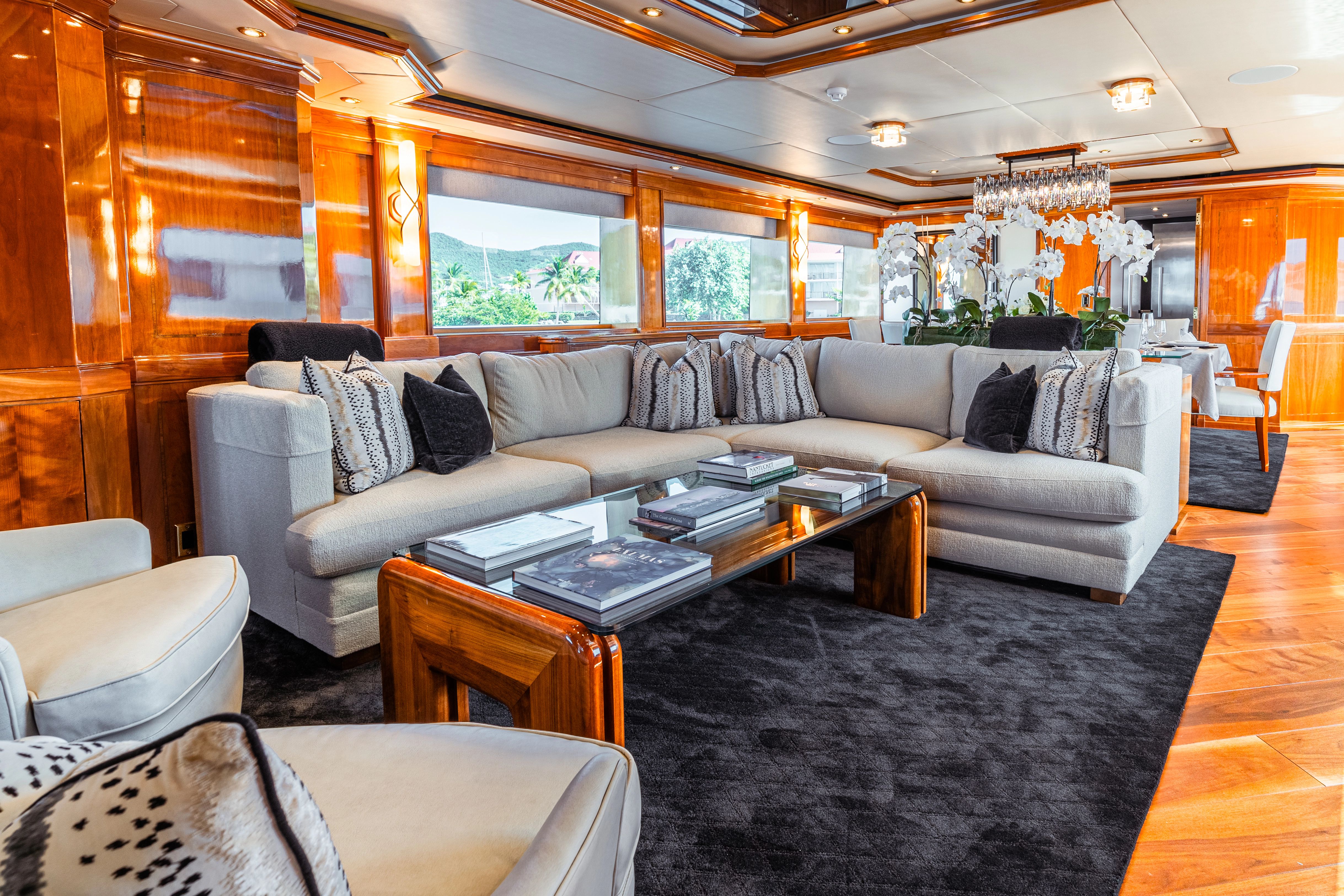 Luxurious salon with large sofas, wood accents, and a glass table on a carpet.