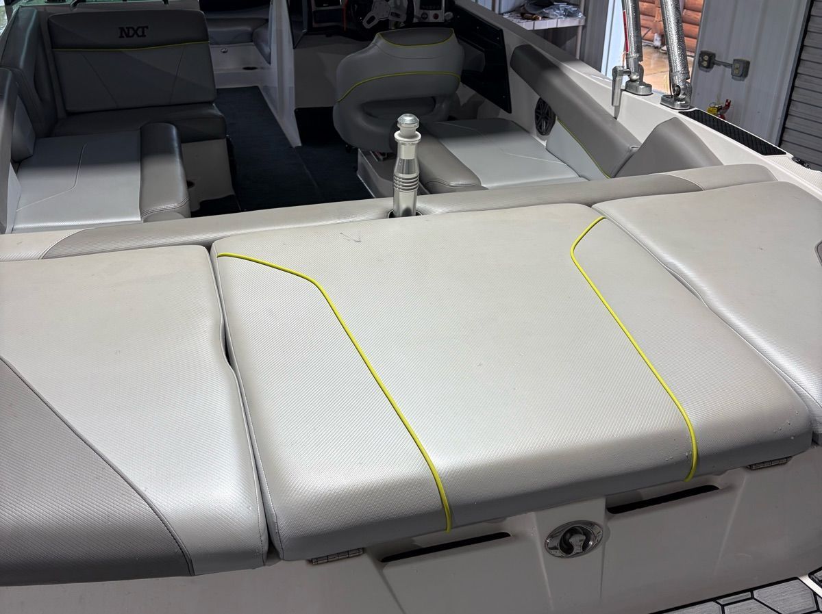 Interior of a MasterCraft NXT22 boat with gray upholstery and yellow stitching.