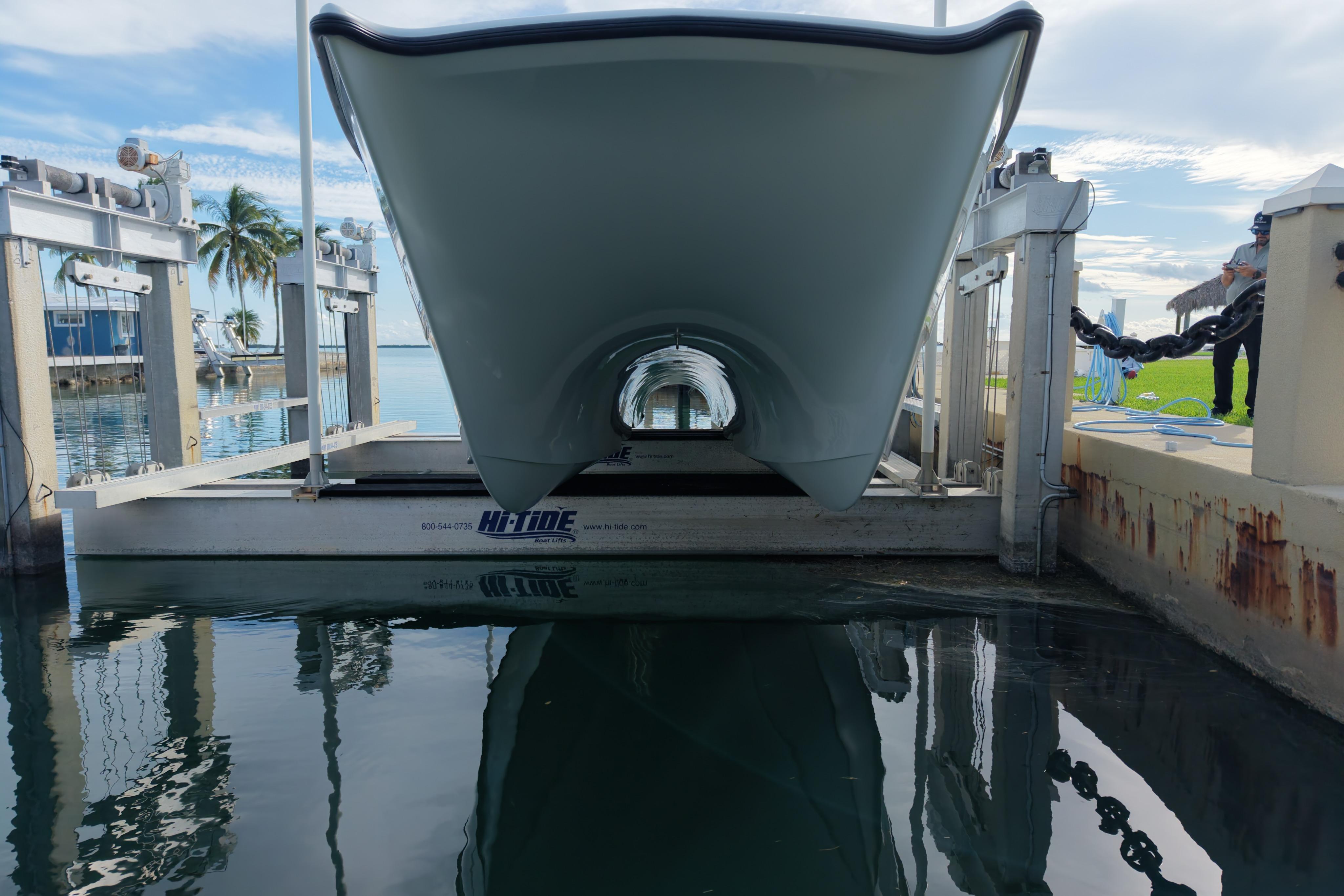 Freeman 34VH 2022 boat on lift, dockside with palm trees and clear sky.