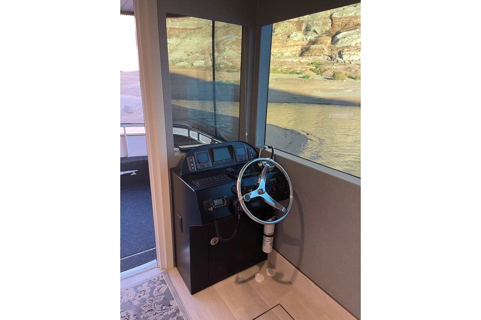 Steering console of 2021 Adonia "The Queen Elizabeth" houseboat with scenic view.