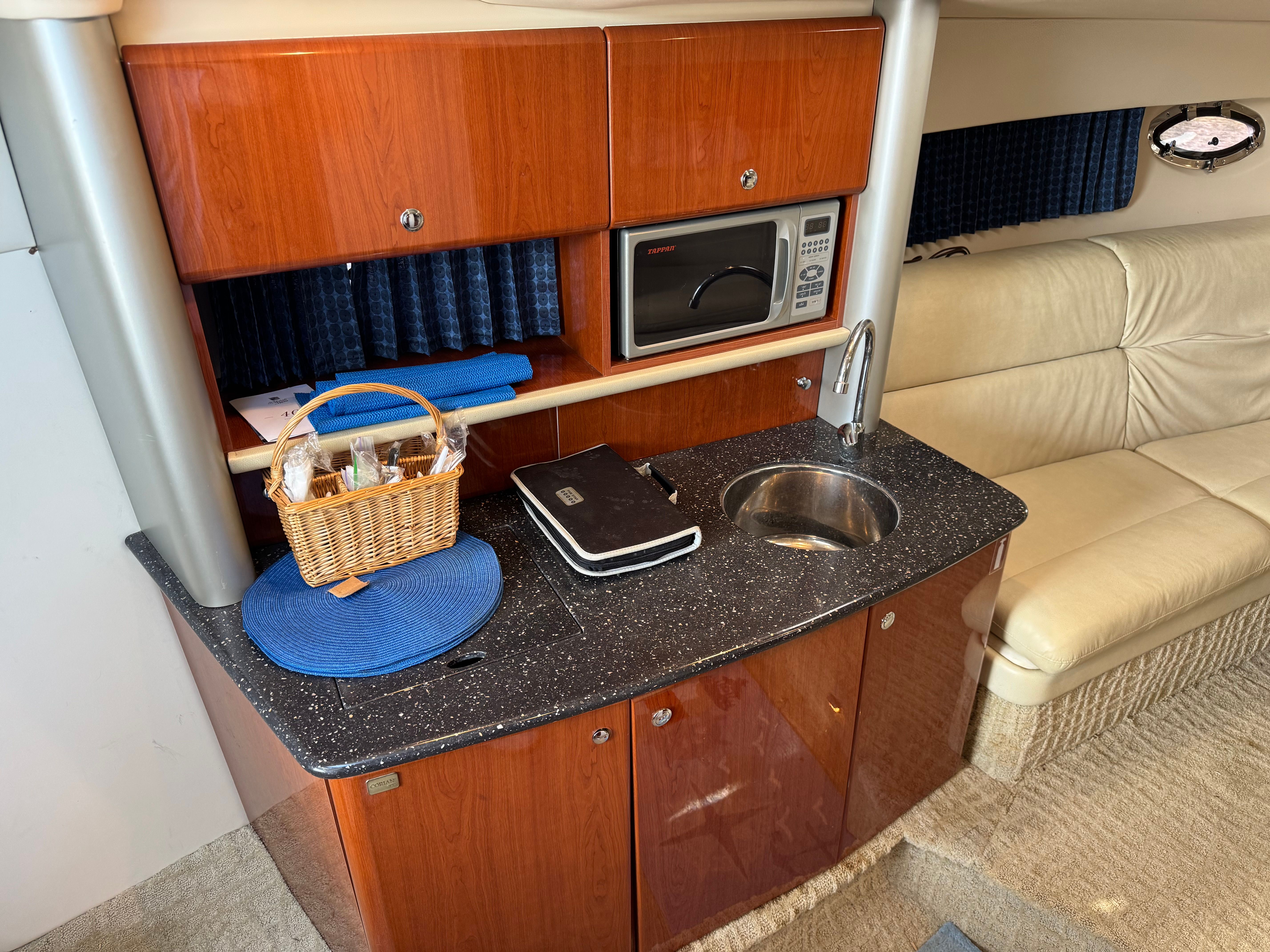 Interior of a yacht with kitchenette, microwave, and leather sofa.