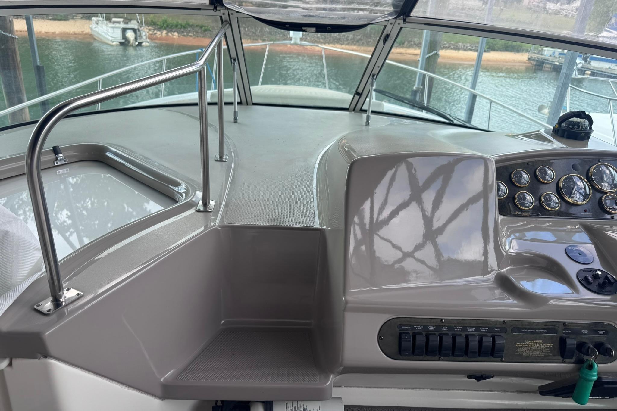 2002 Cruisers Yachts 3275 Express helm with gauges and controls, docked by the water.