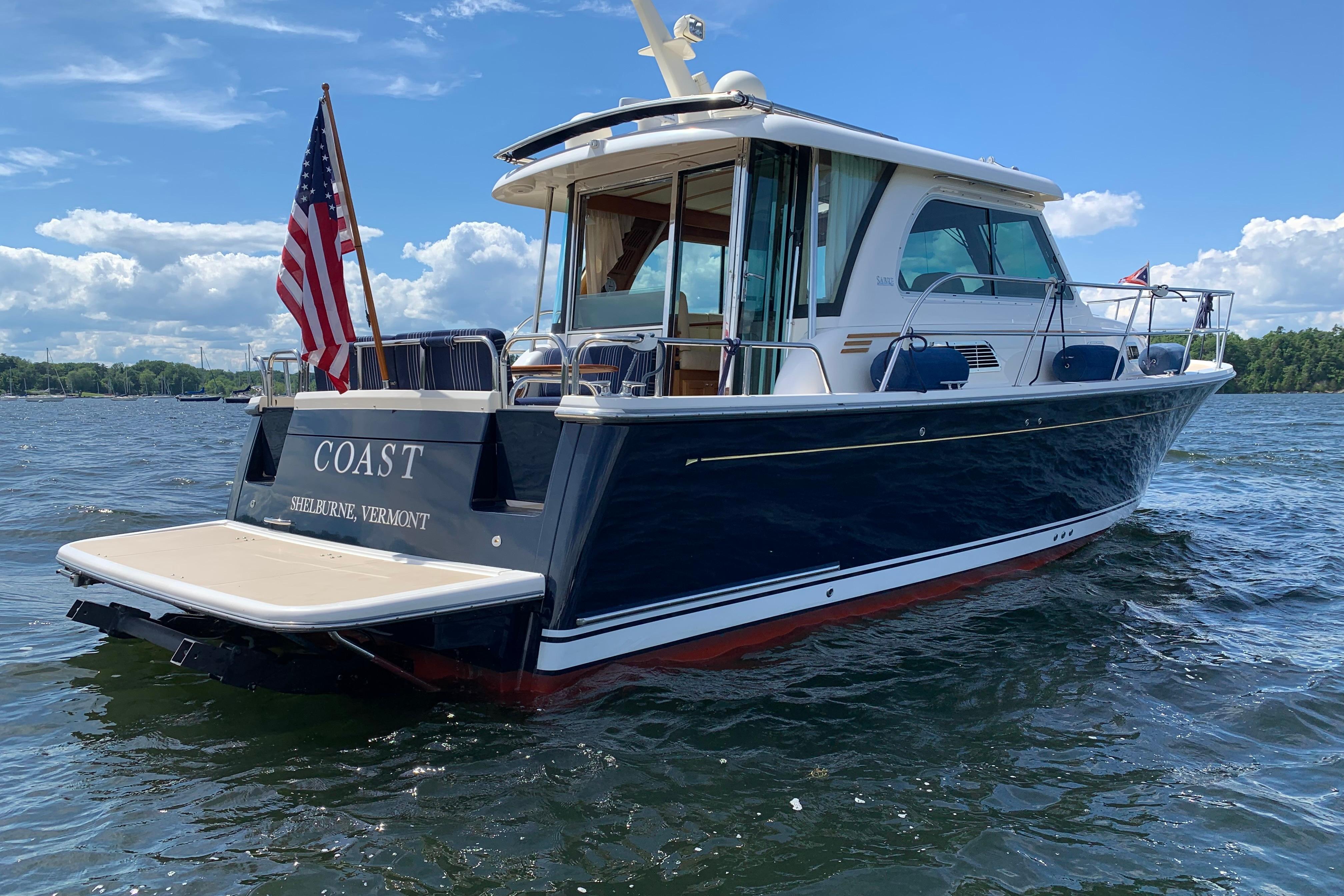 2015 Sabre 38 Salon Express boat on water, American flag, sunny day.